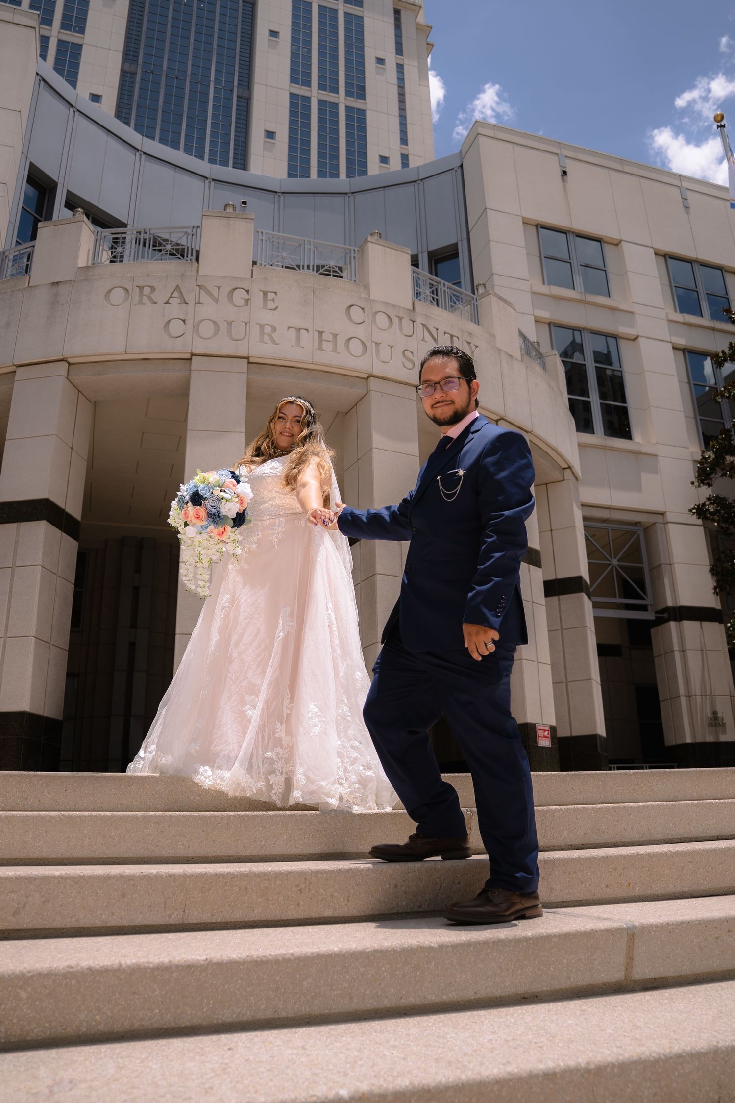 Bride and groom pose on steps outside Orange County Courthouse after their wedding ceremony.
