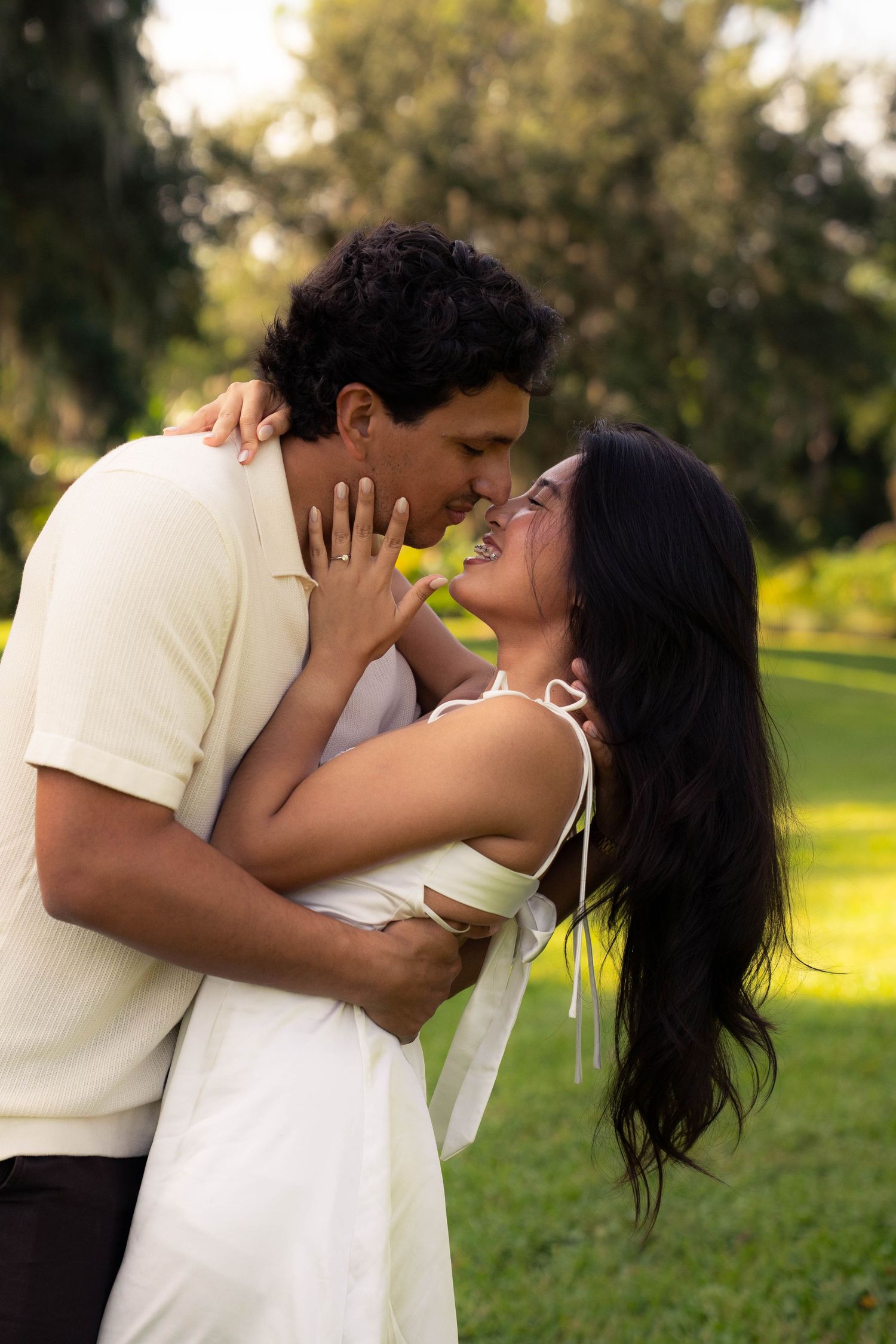Happy couple embracing and laughing together in a green outdoor park setting.
