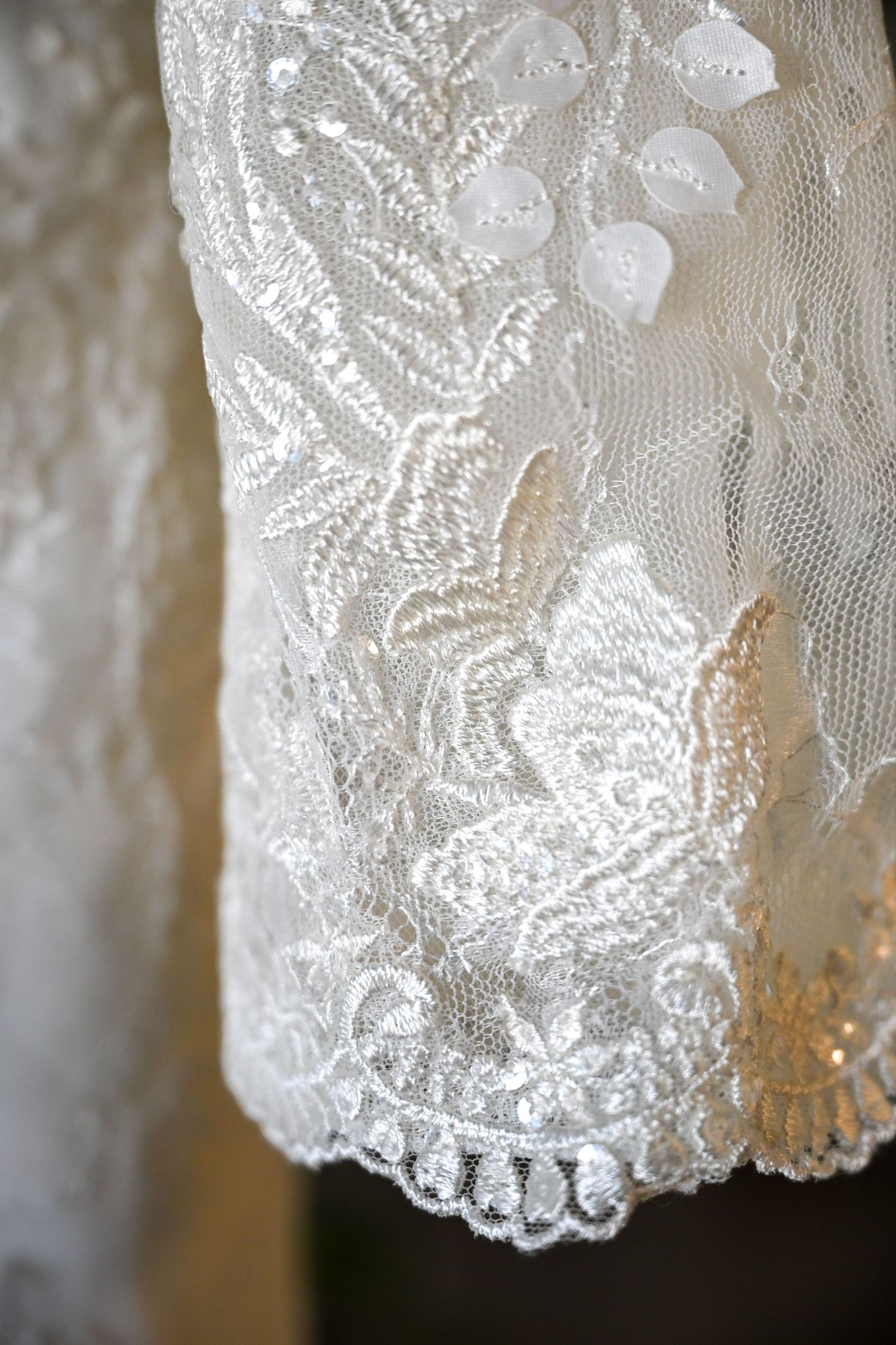 Close-up detail of intricate white lace embroidery on elegant bridal wedding gown.