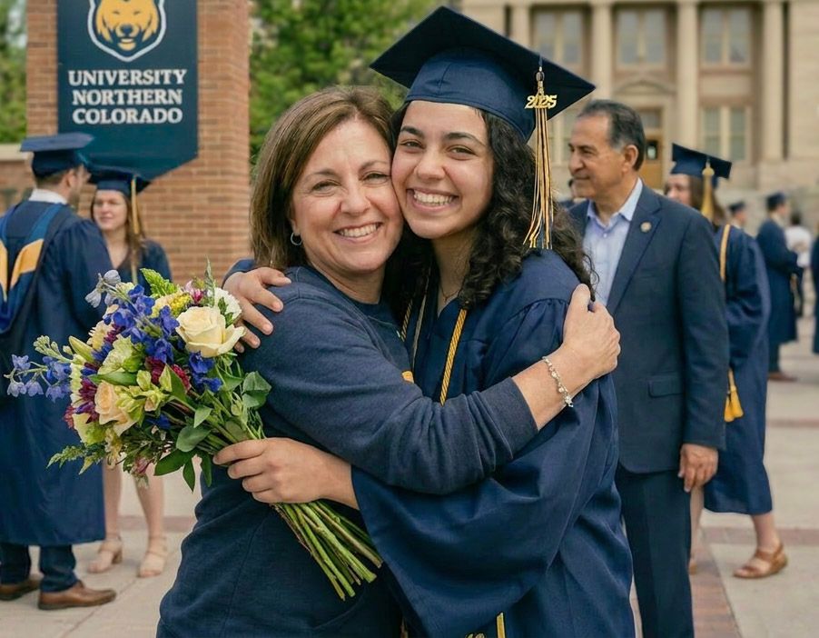 Graduate in University of Northern Colorado cap and gown hugging a woman holding flowers.
