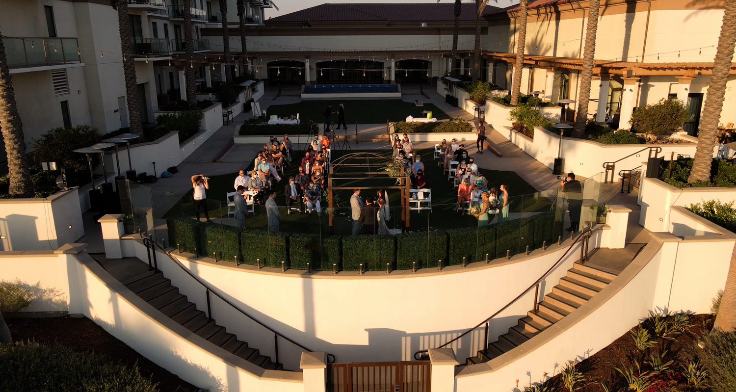 Aerial view of an outdoor gathering at a modern hotel courtyard at sunset.
