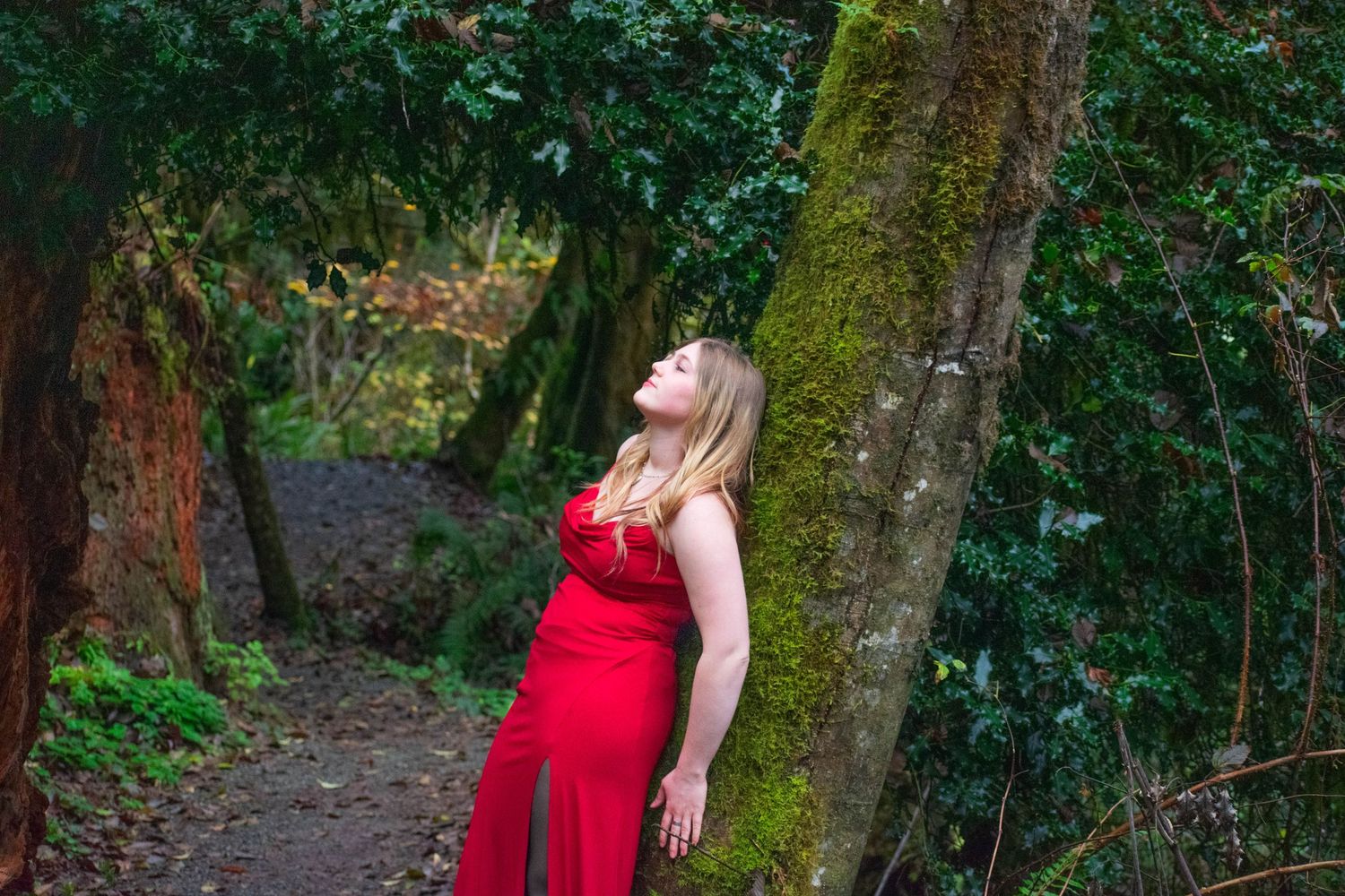A photo of a woman leaning against a tree.