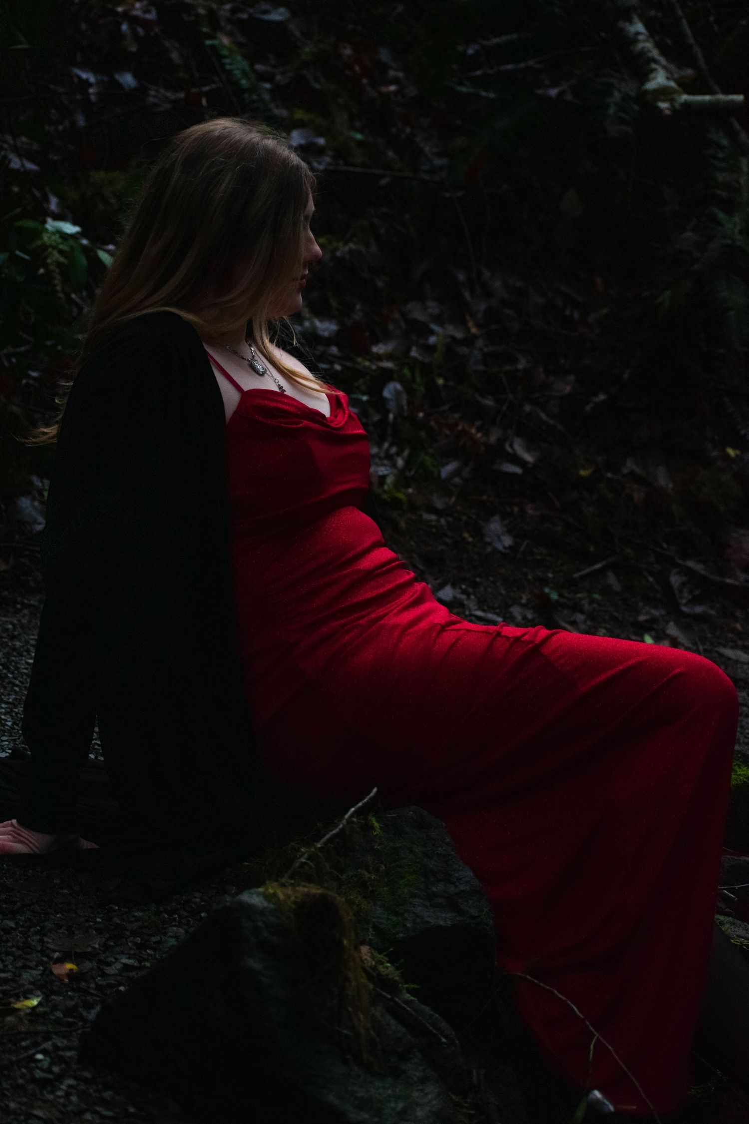 A photo of a woman sitting in the forest.
