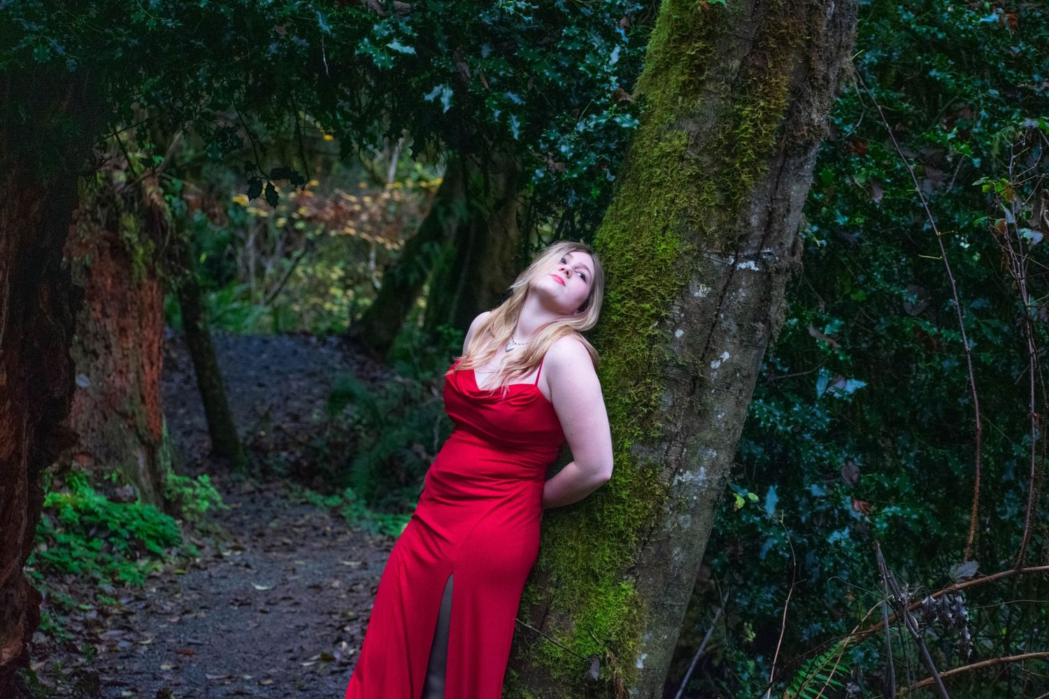 A photo of a woman leaning against a tree.