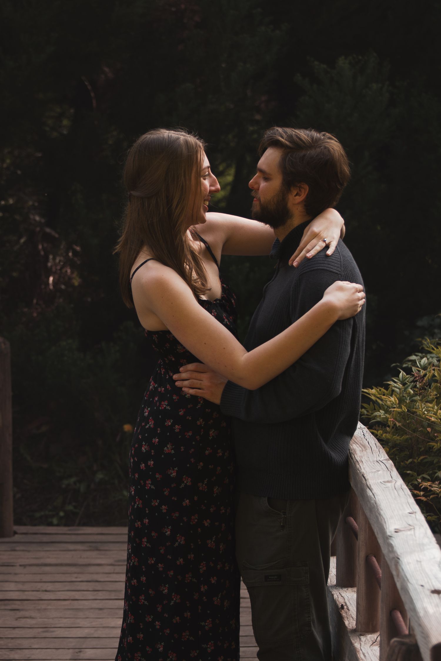 A photo of a couple holding each other on a bridge.