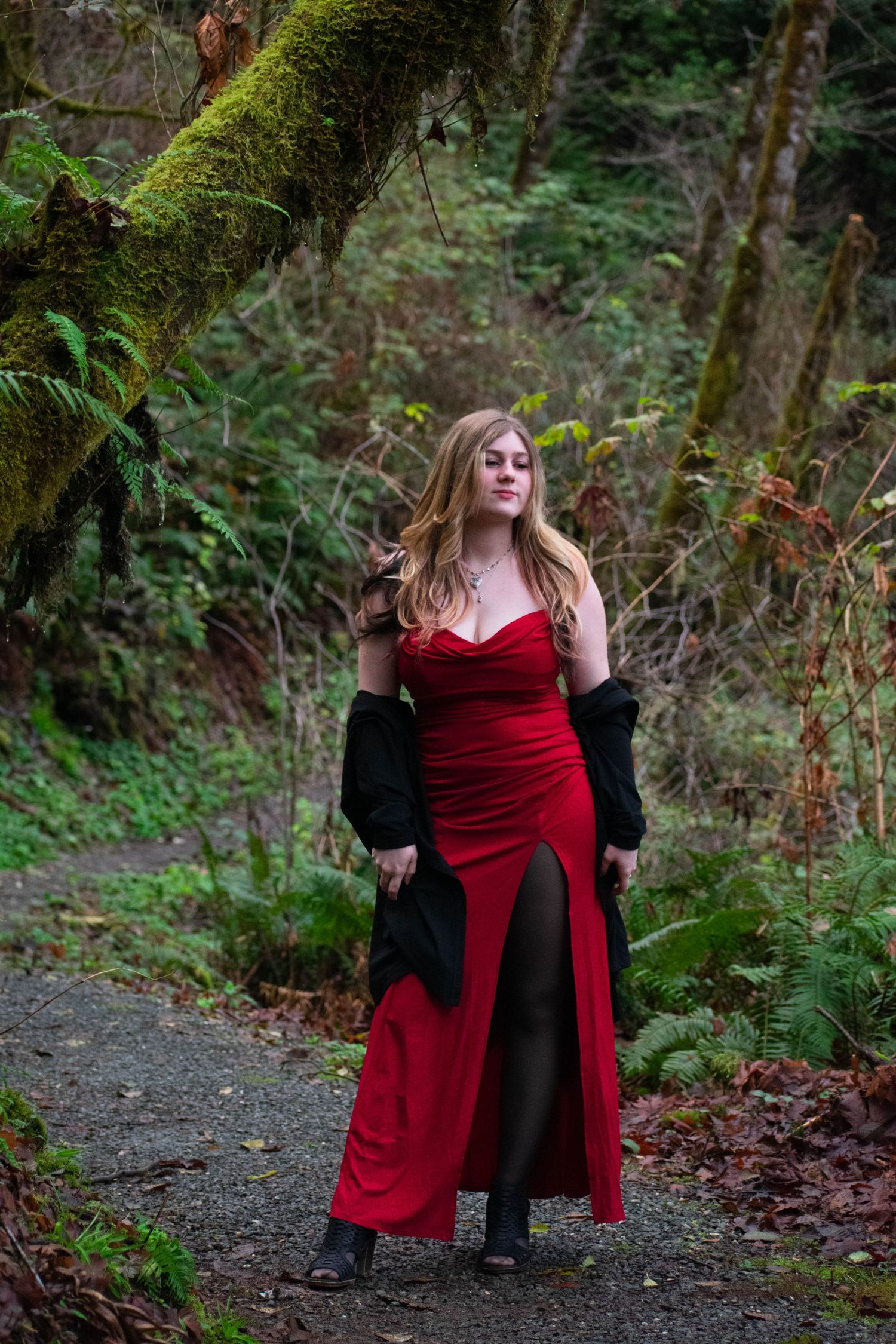 A photo of a woman standing in the forest.