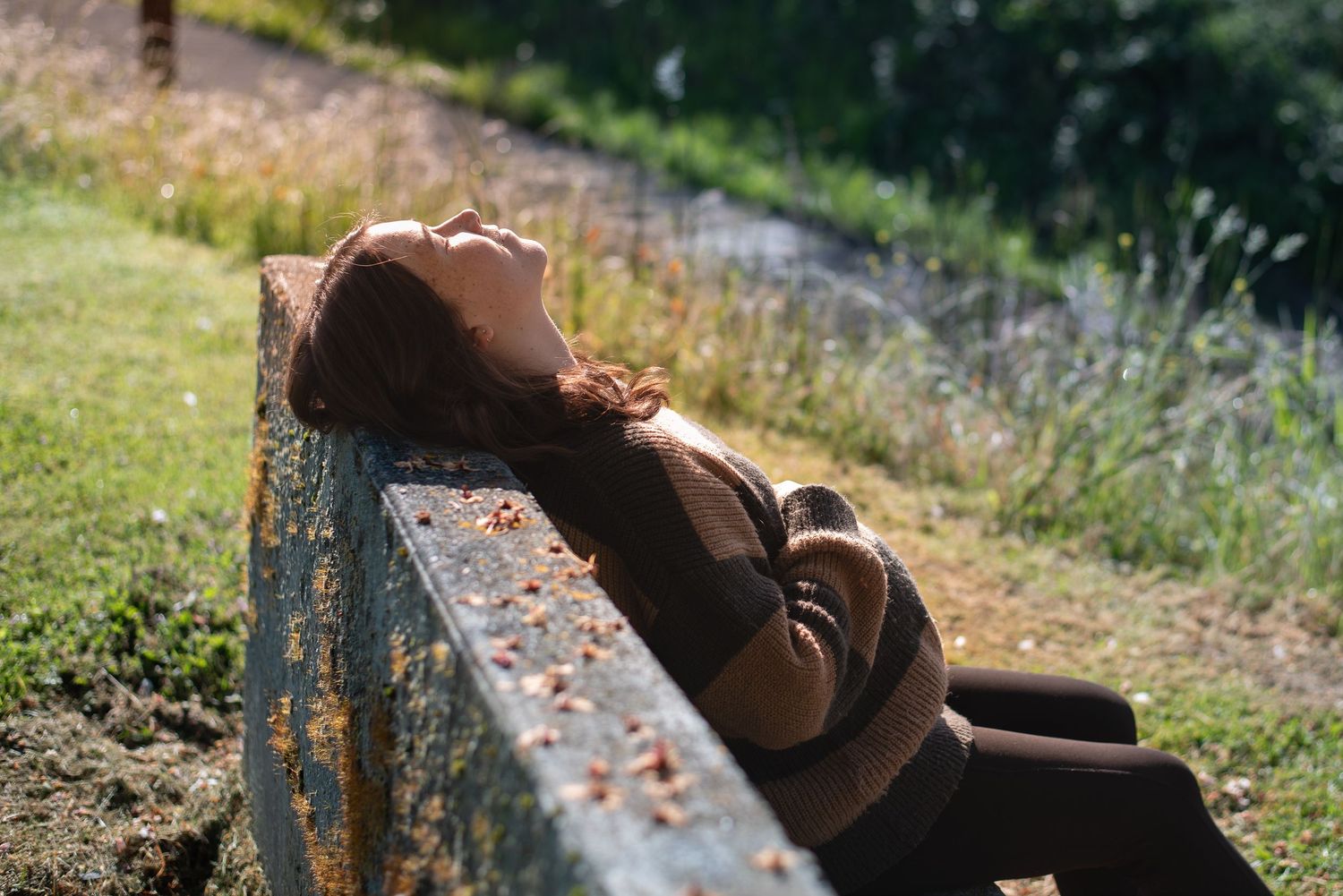 A photo of a pregnant woman leaning back in a bench.