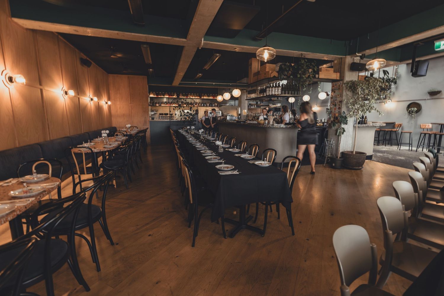Elegant restaurant dining room with long table setup and warm ambient lighting.