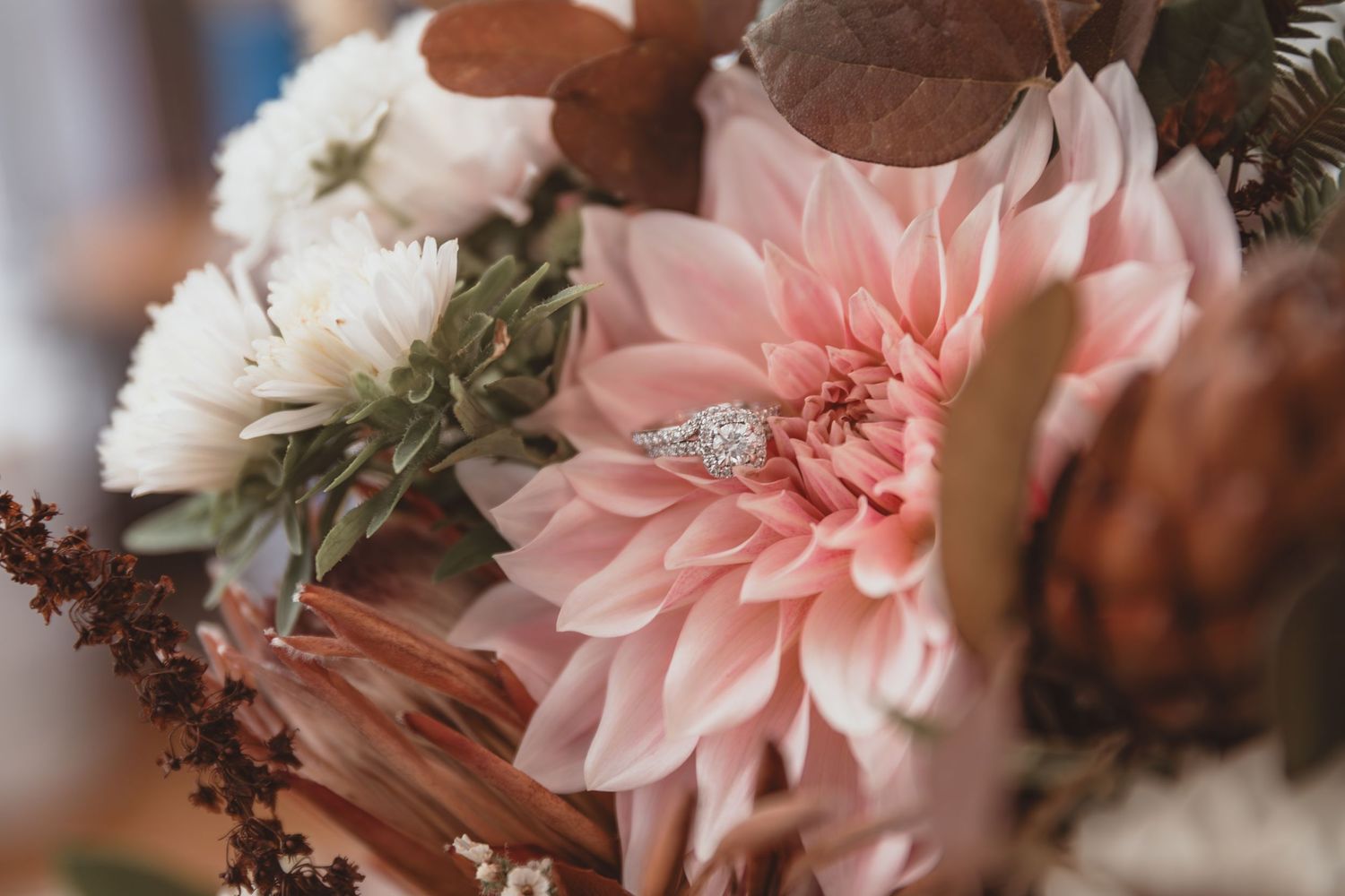 Diamond engagement ring nestled in a lush pink dahlia bridal bouquet.
