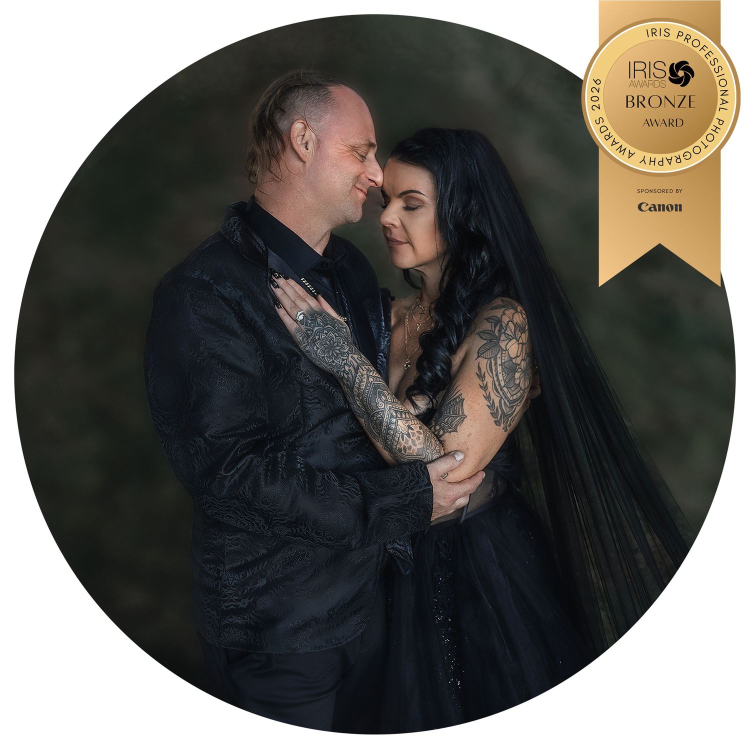 A couple in black wedding attire embrace romantically, the bride wearing a black veil and tattoos, award-winning photo, by Charly Baty.