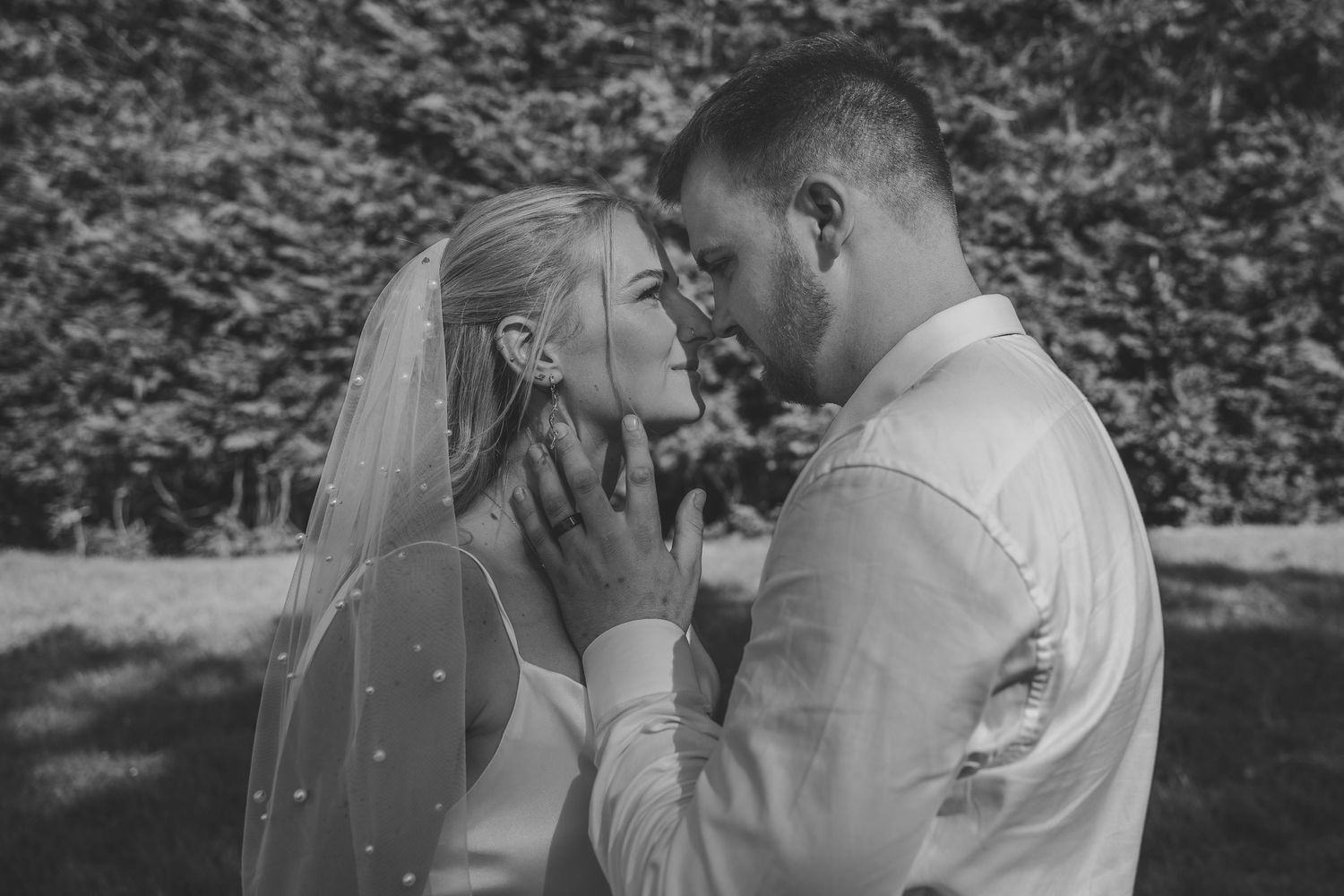 Black and white romantic portrait of bride and groom sharing an intimate moment.