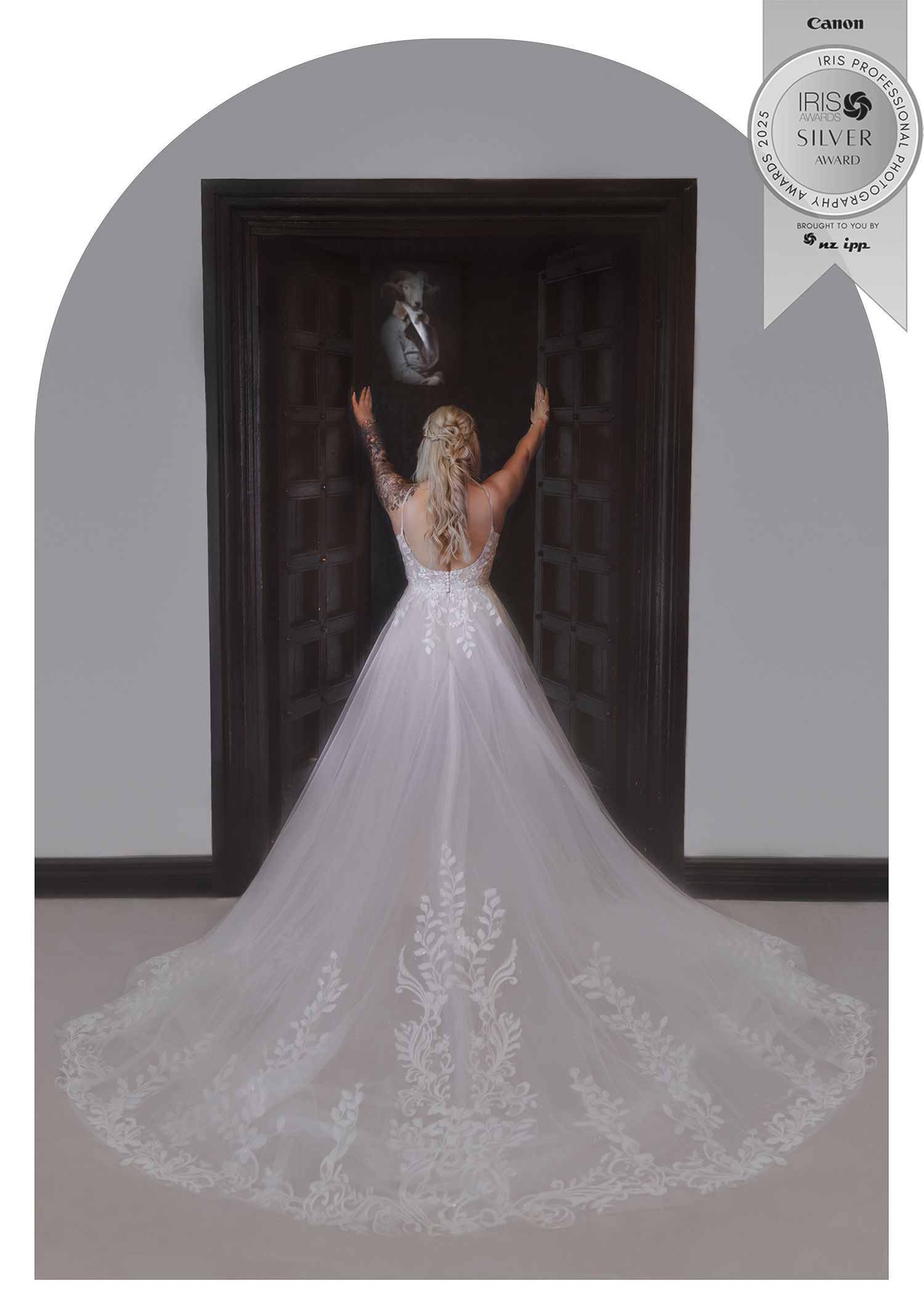 Bride in elegant lace wedding gown with long train, viewed from behind, standing at ornate dark doorway.
