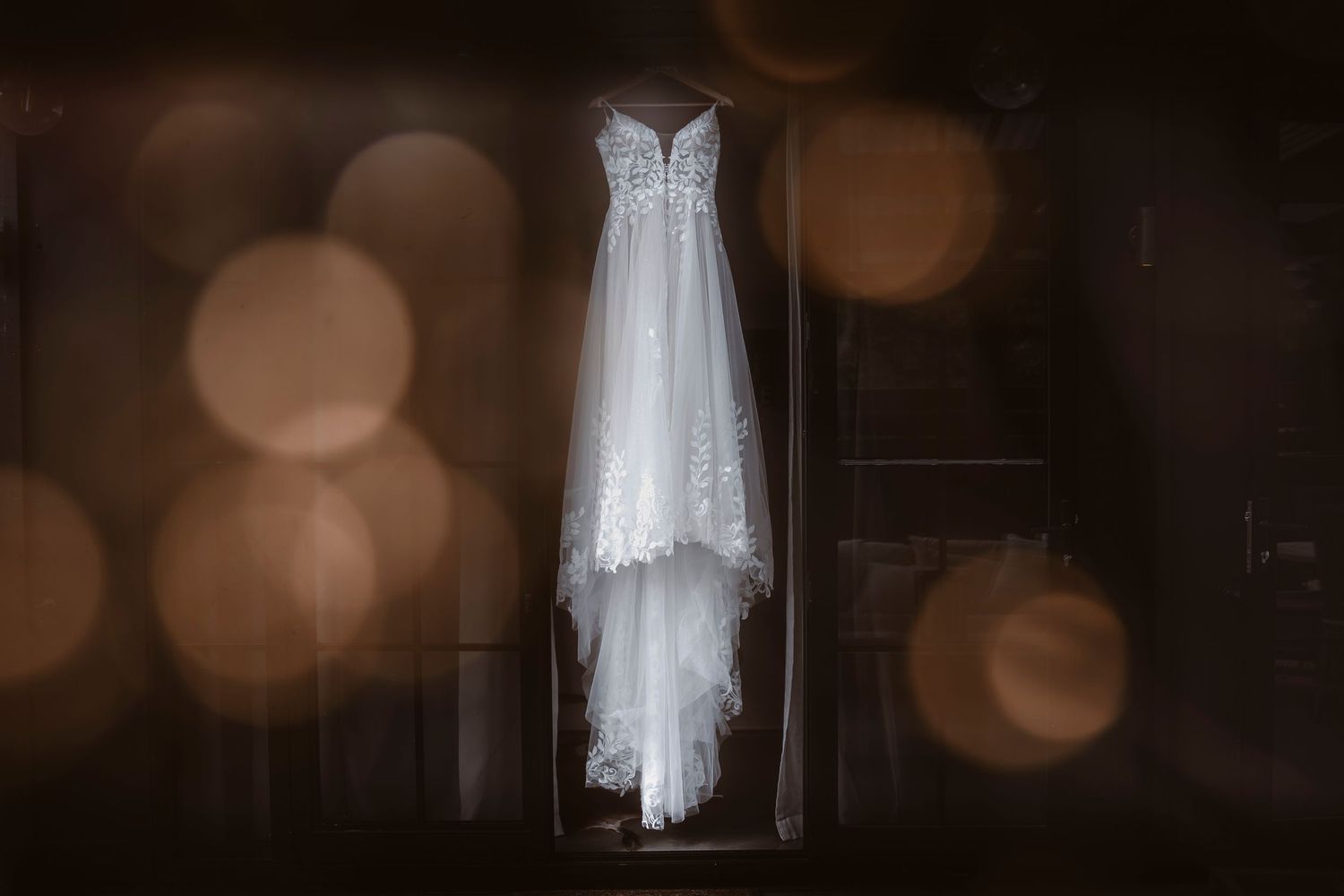 Elegant wedding dress hanging in soft bokeh light creating a dreamy atmosphere.