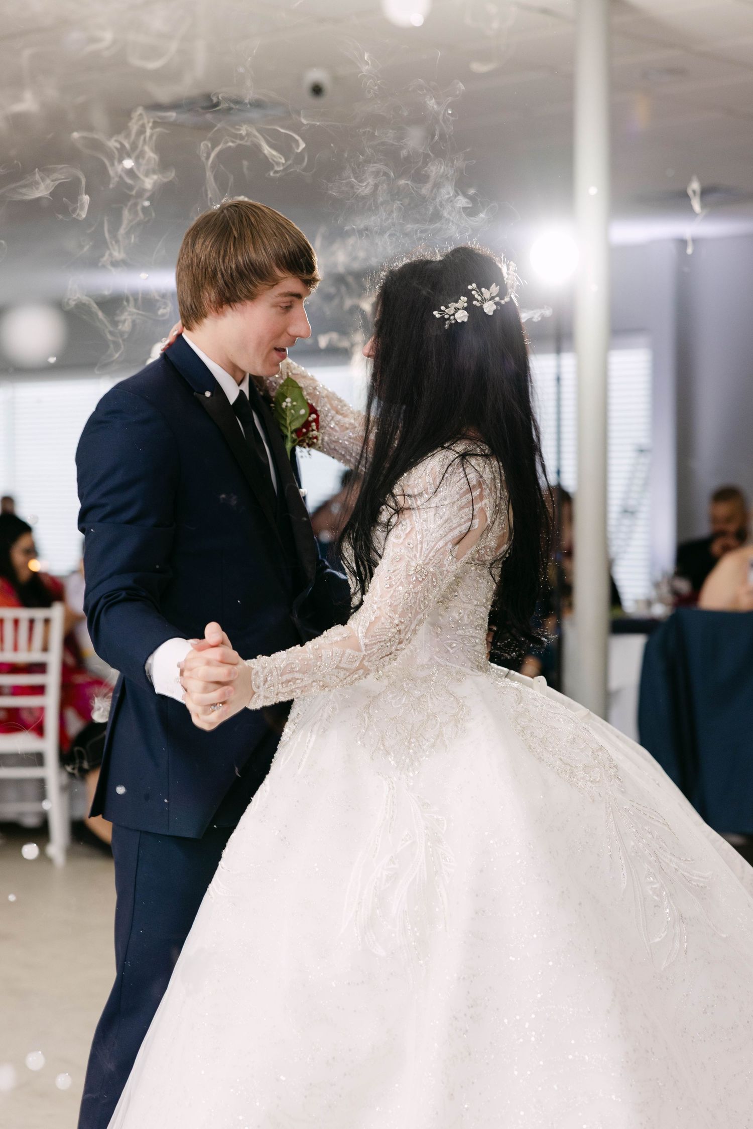 Bride in ornate long-sleeve ballgown and groom in navy suit sharing first dance with smoke effects at the Atrium in Butler, Pennsylvania.