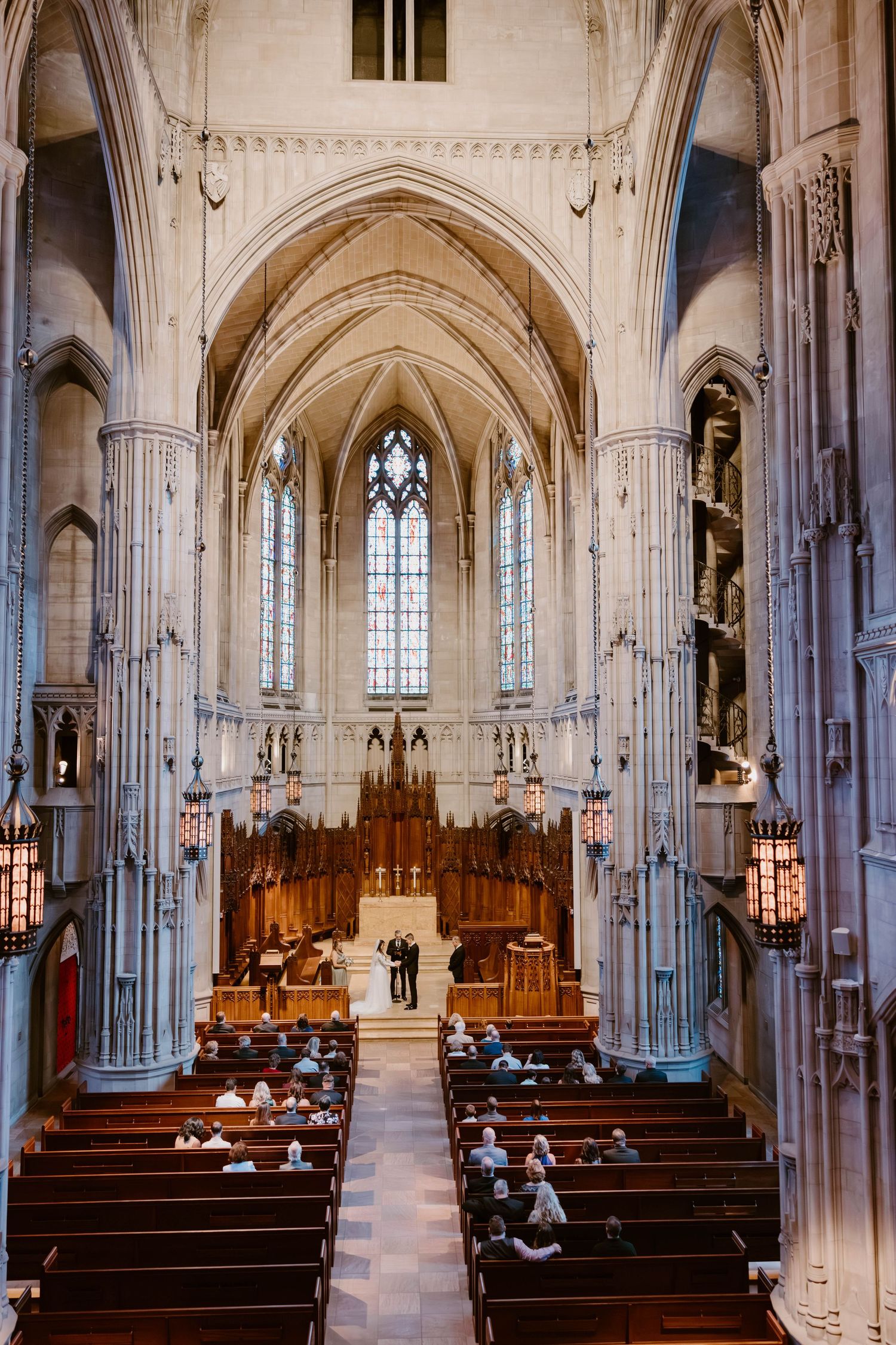 Elegant Gothic cathedral interior with vaulted ceilings, stone columns, and a couple standing at the wooden altar.