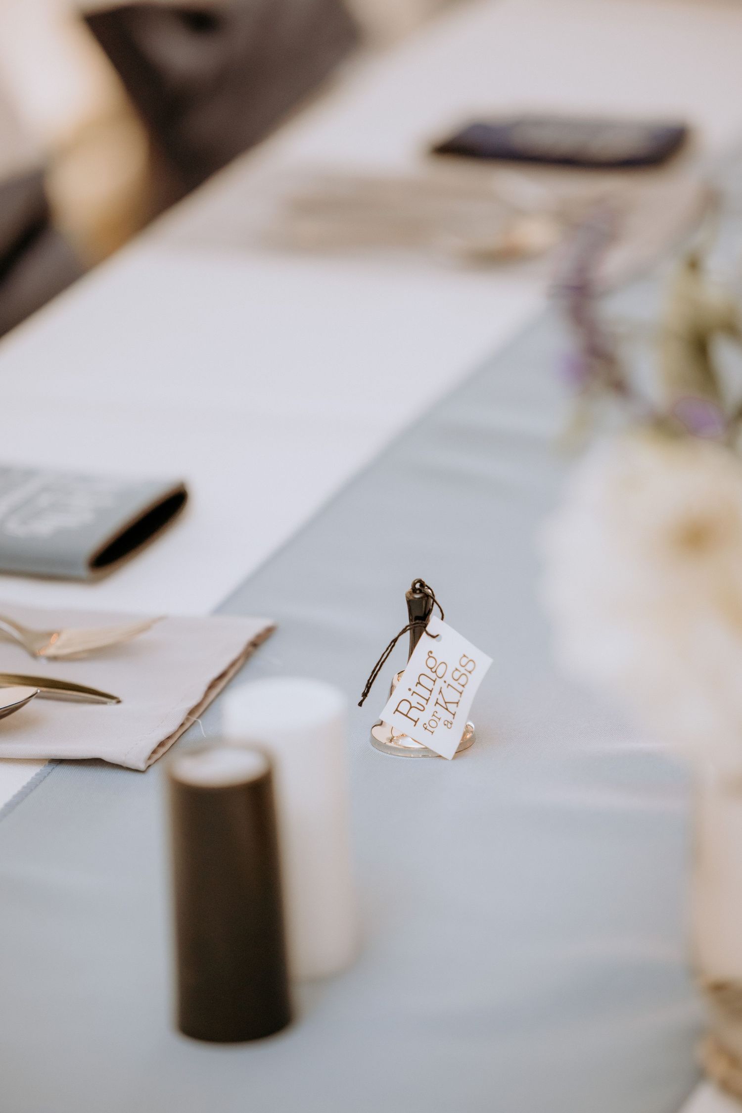 Wedding reception table with light blue runner, small place card favor, and elegant place settings.