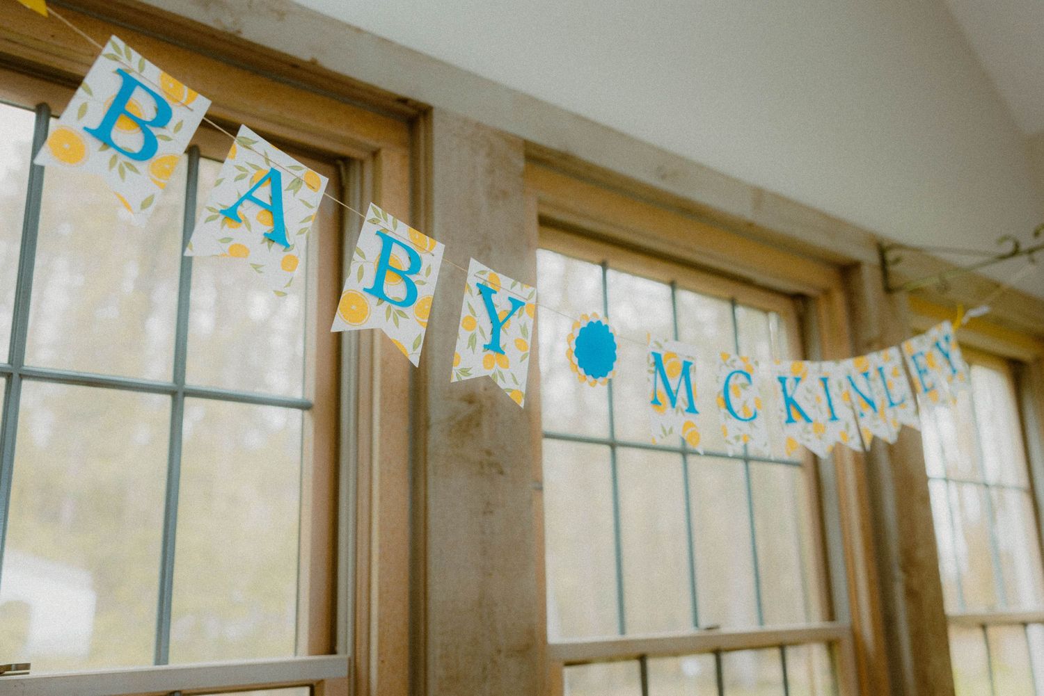 Colorful Baby McKinley banner hanging on wooden window frames at a baby shower celebration.