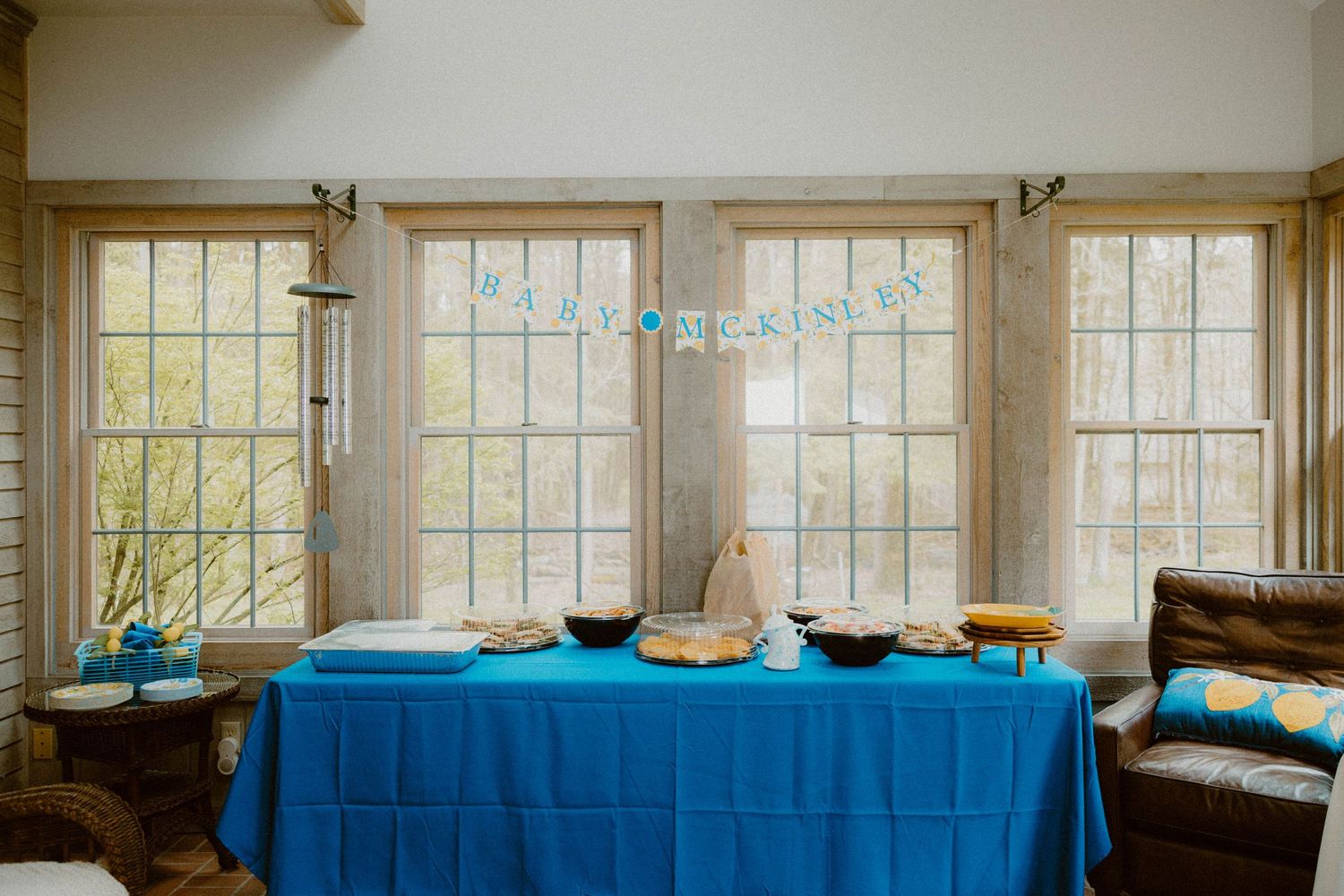 Blue tablecloth party setup with Happy Birthday banner hanging in front of bright windows.
