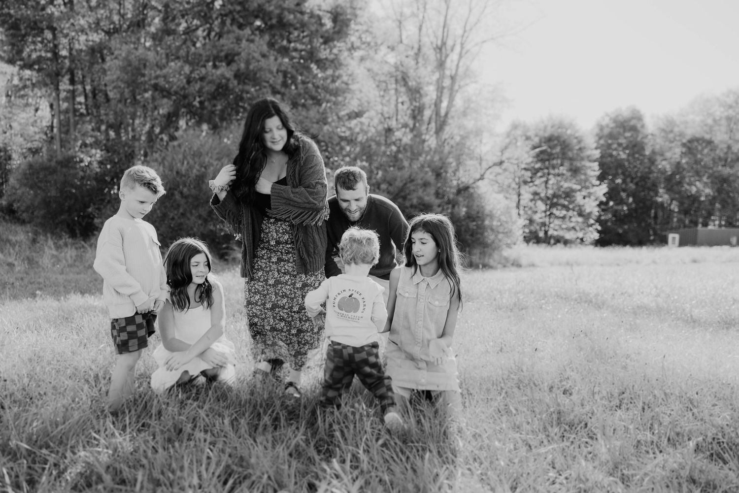 Black and white photo of a family with young children gathered together in an open grassy field.
