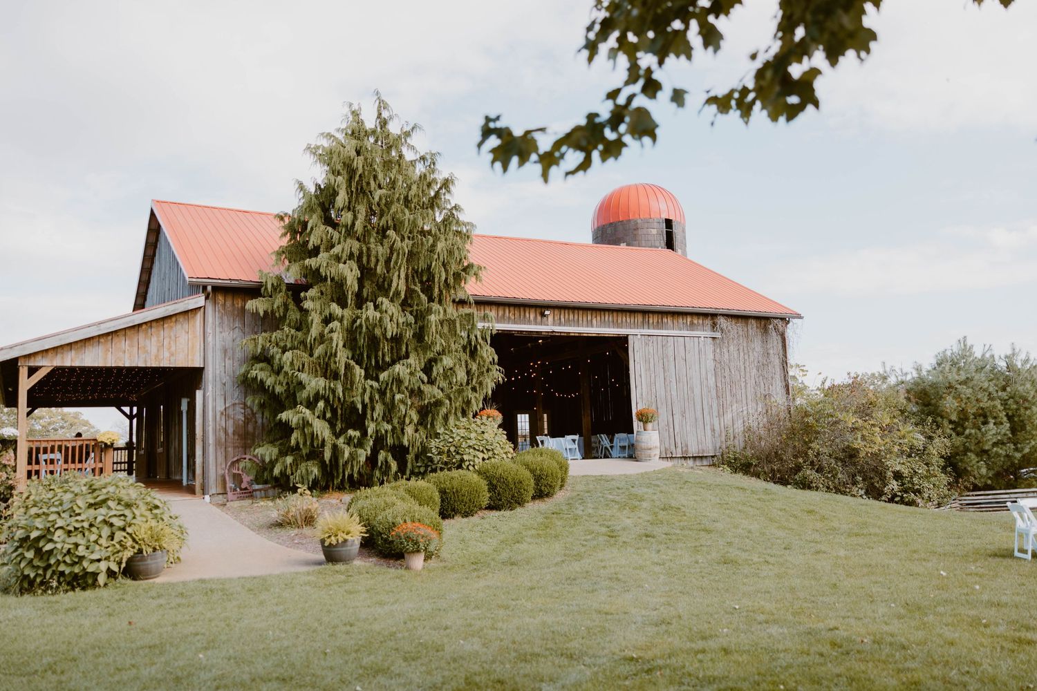 Rustic barn wedding venue with red silo, lush greenery, and charming countryside landscape.