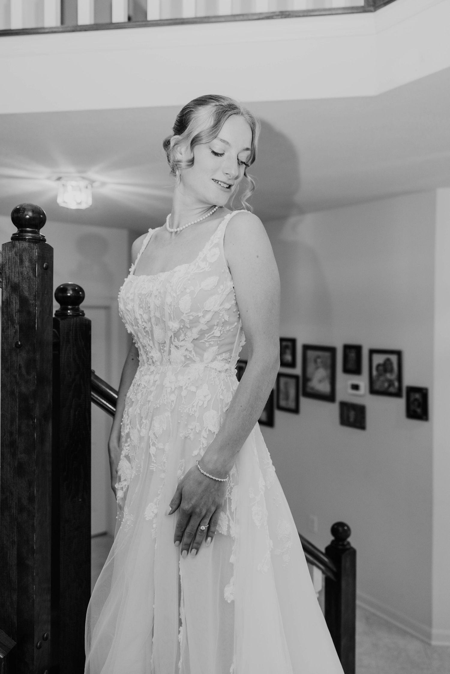 Black and white photo of a bride in a lace wedding gown posing gracefully on a staircase.