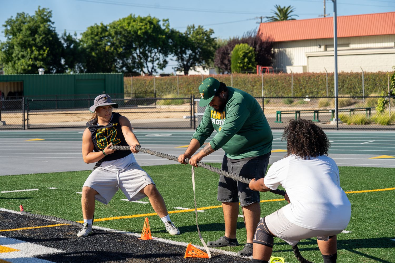 Athletes training with resistance bands on a football field during an outdoor sports practice session.
