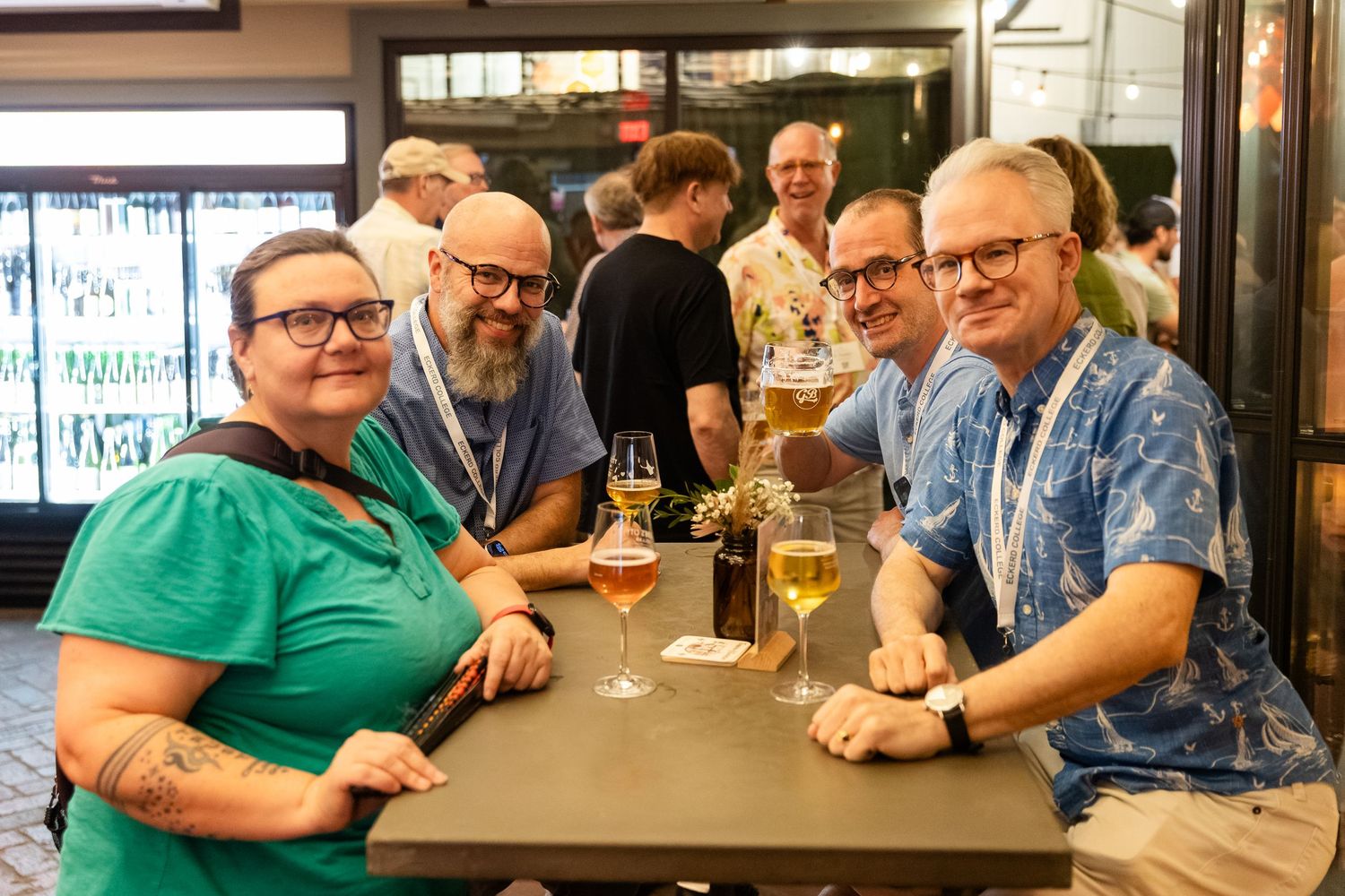 Group of friends smiling and enjoying drinks together at an indoor bar or restaurant social gathering.