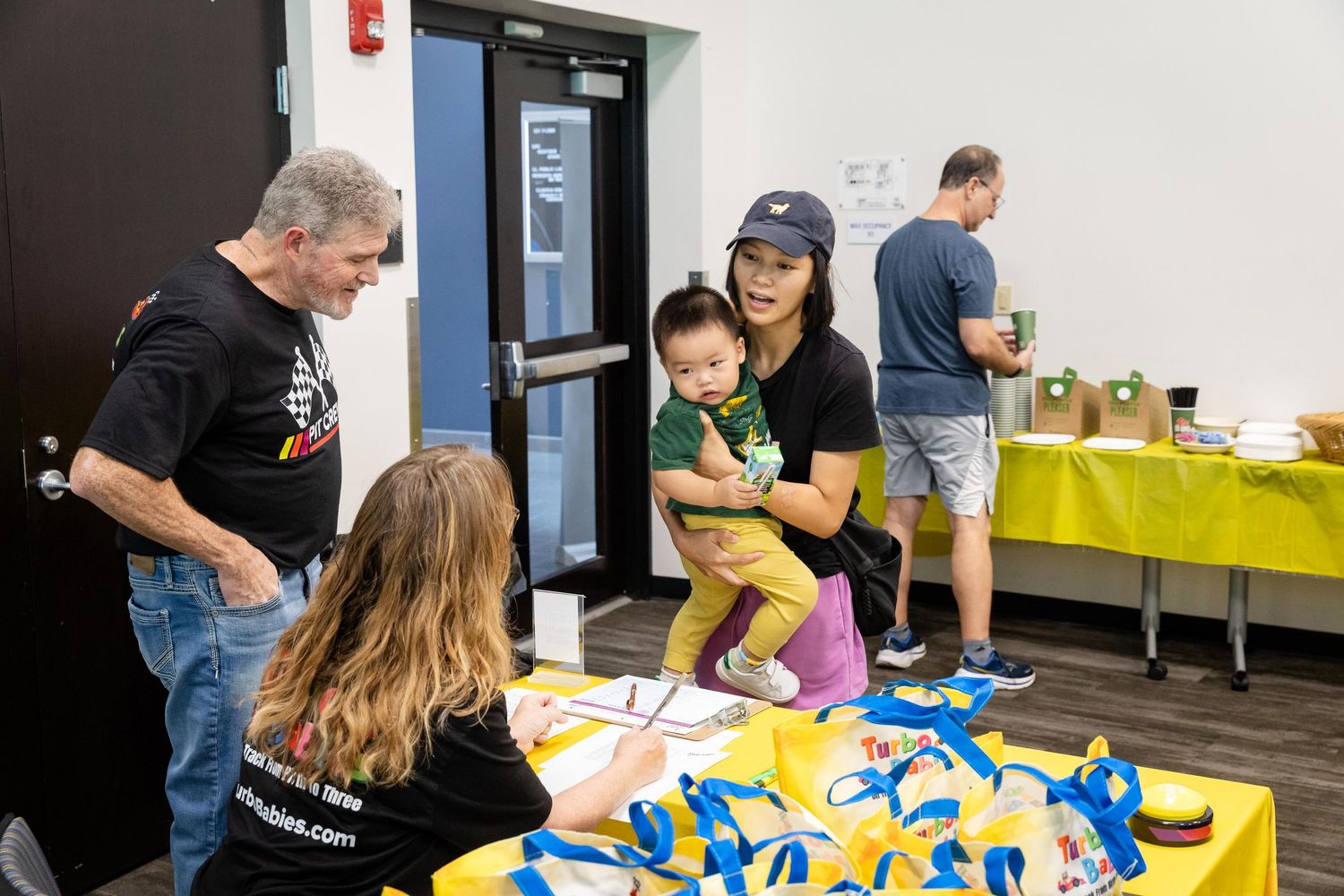 People gather at a registration table with blue lanyards during a community event indoors.
