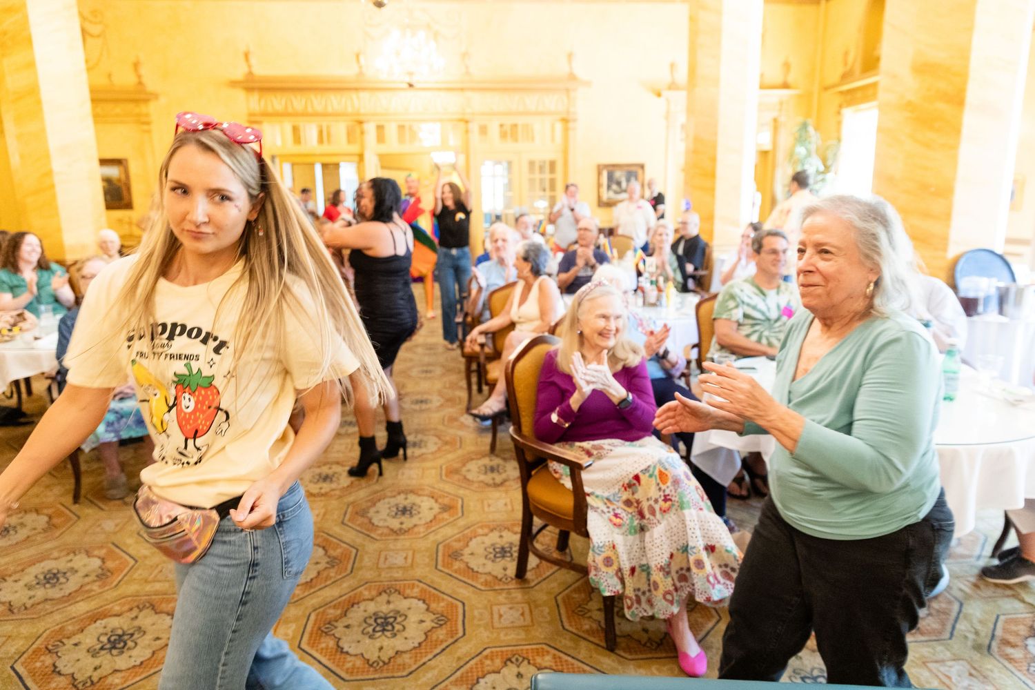 Young woman and older woman dancing at a festive senior community indoor gathering event.