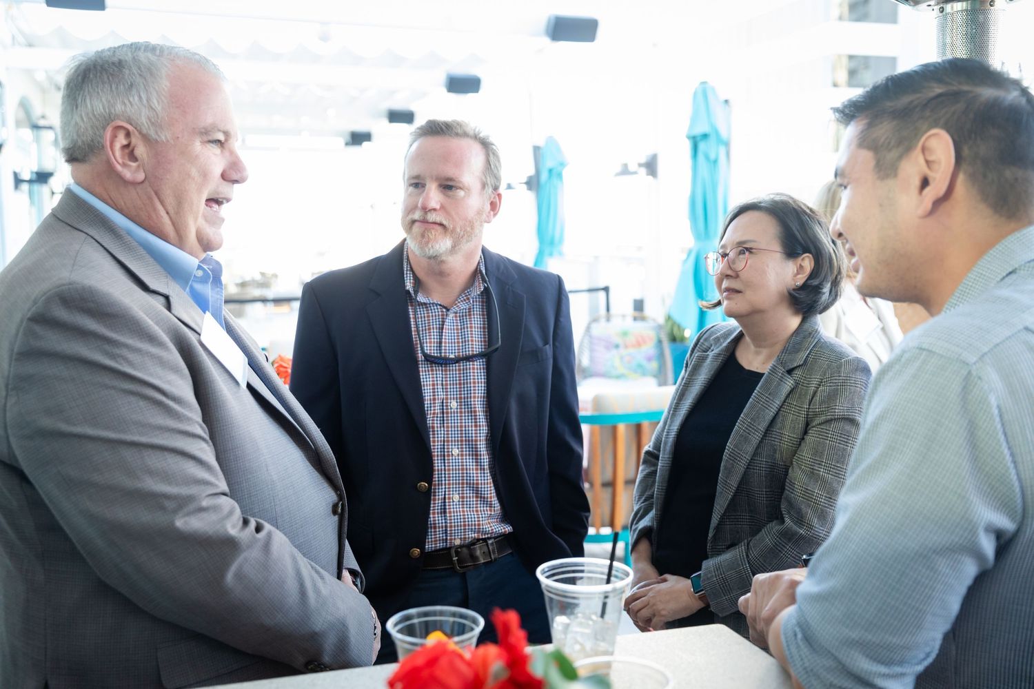 Four professionals networking around a table at an outdoor business event.
