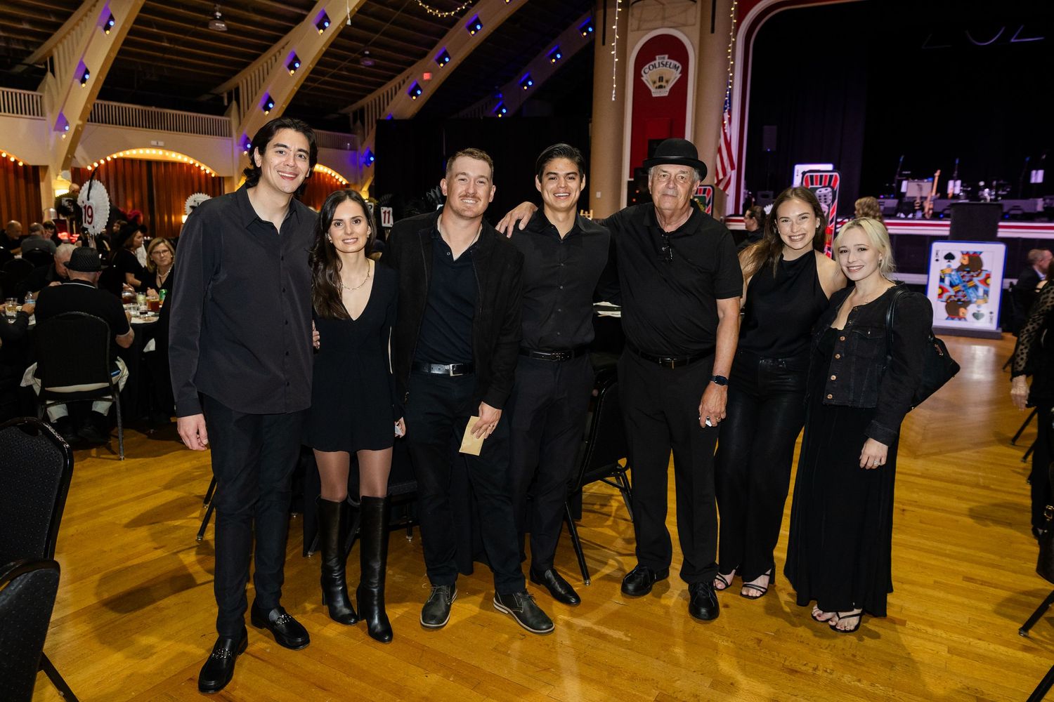 Group of seven people dressed in black posing together at a formal casino night event.