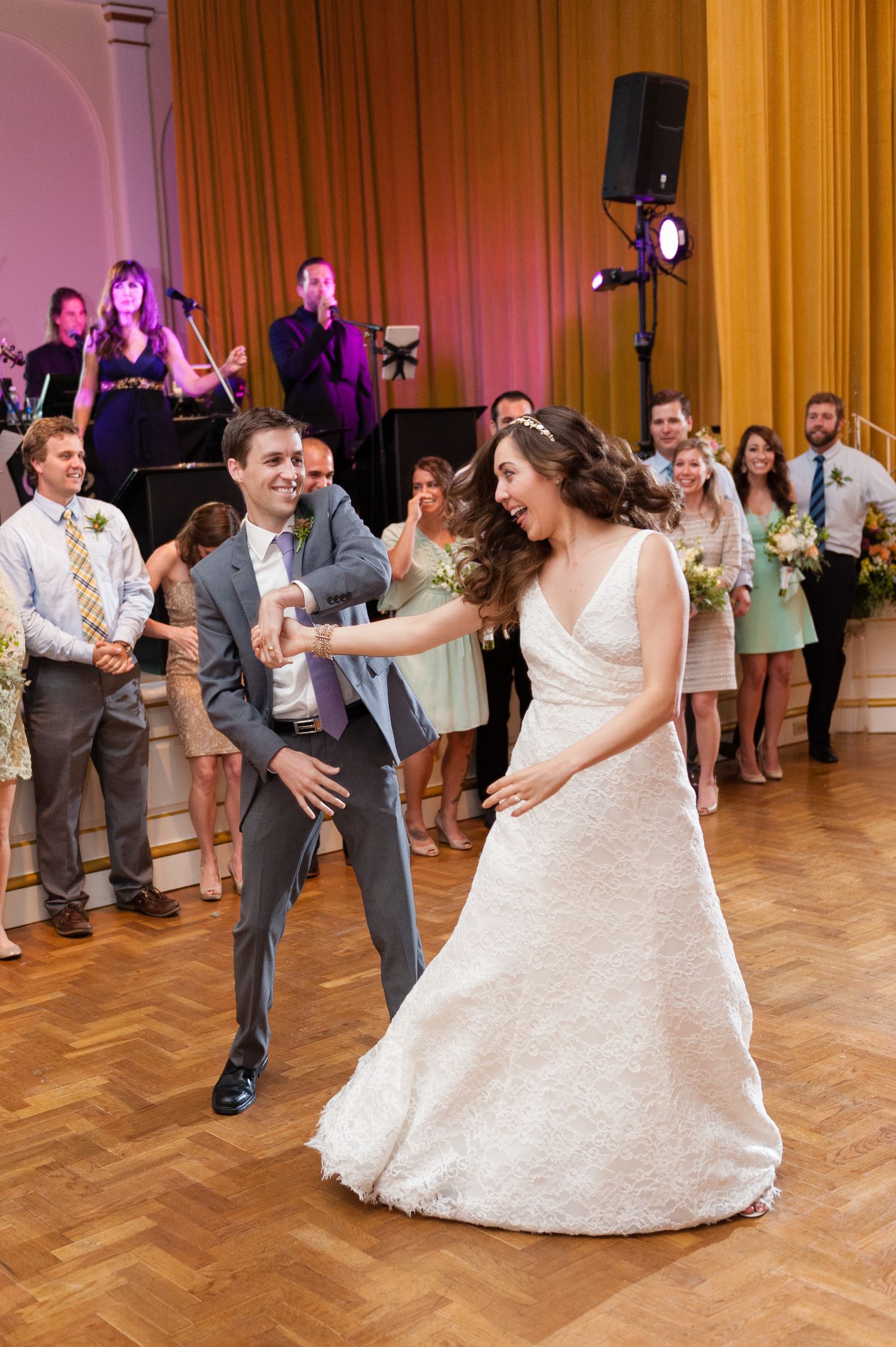 Bride and groom share joyful first dance at elegant wedding reception with live band.