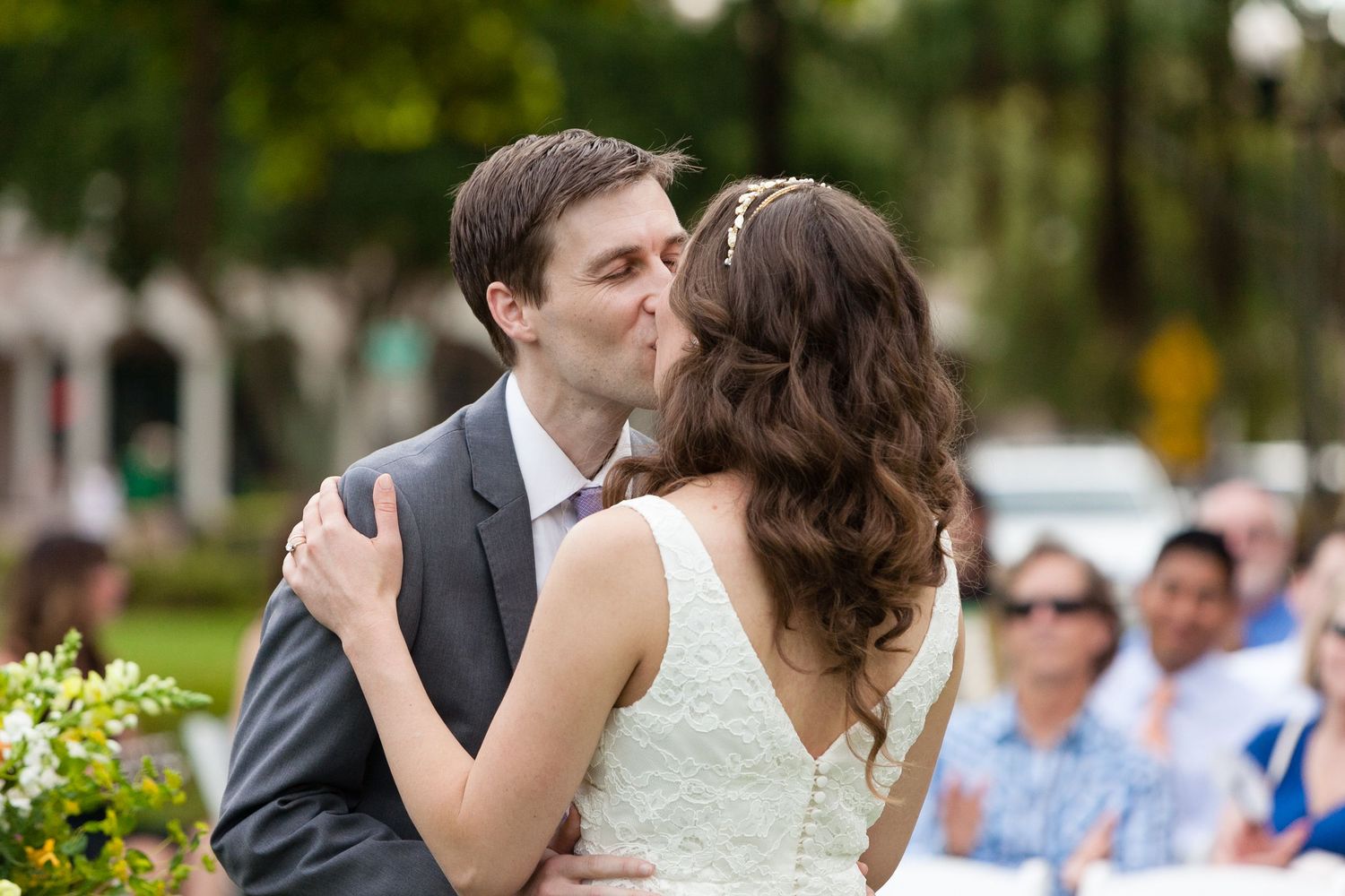 Bride and groom sharing their first kiss during an outdoor wedding ceremony.