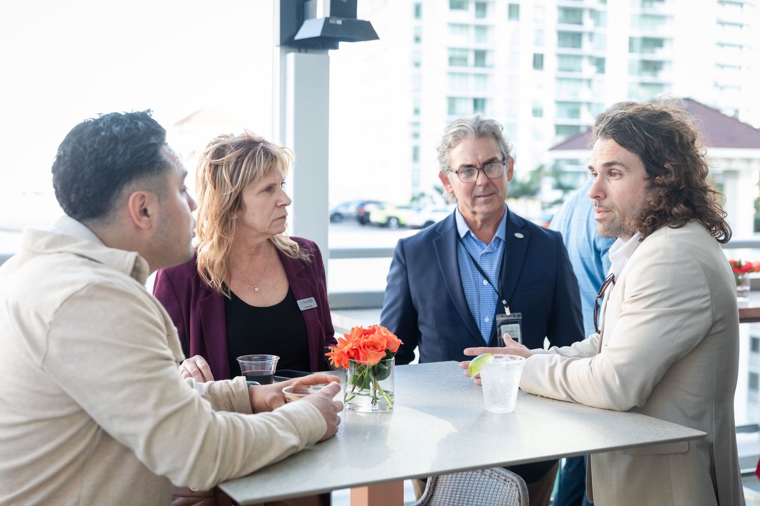 Four professionals networking and conversing around a white table at an Orlando Health corporate event.