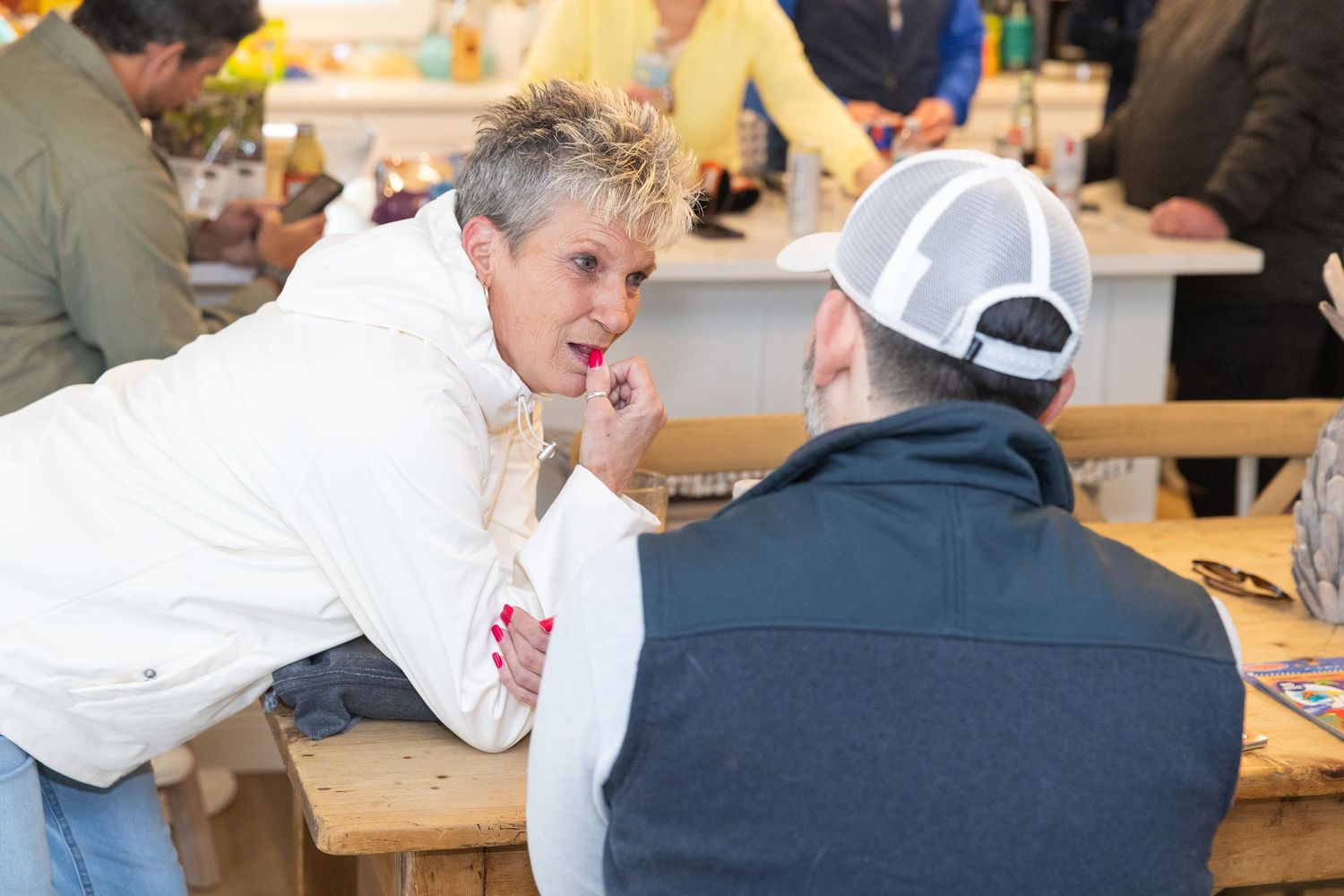 Two people having an intimate conversation at a rustic wooden table indoors.