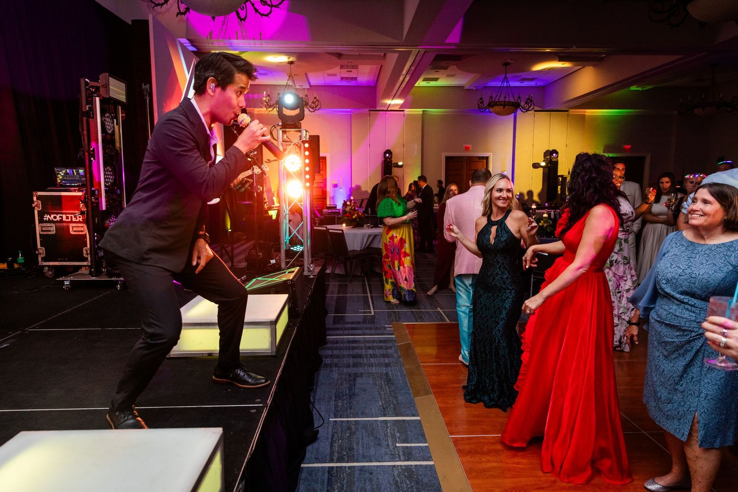 Energetic performer on stage entertaining elegantly dressed guests at a glamorous formal gala event.