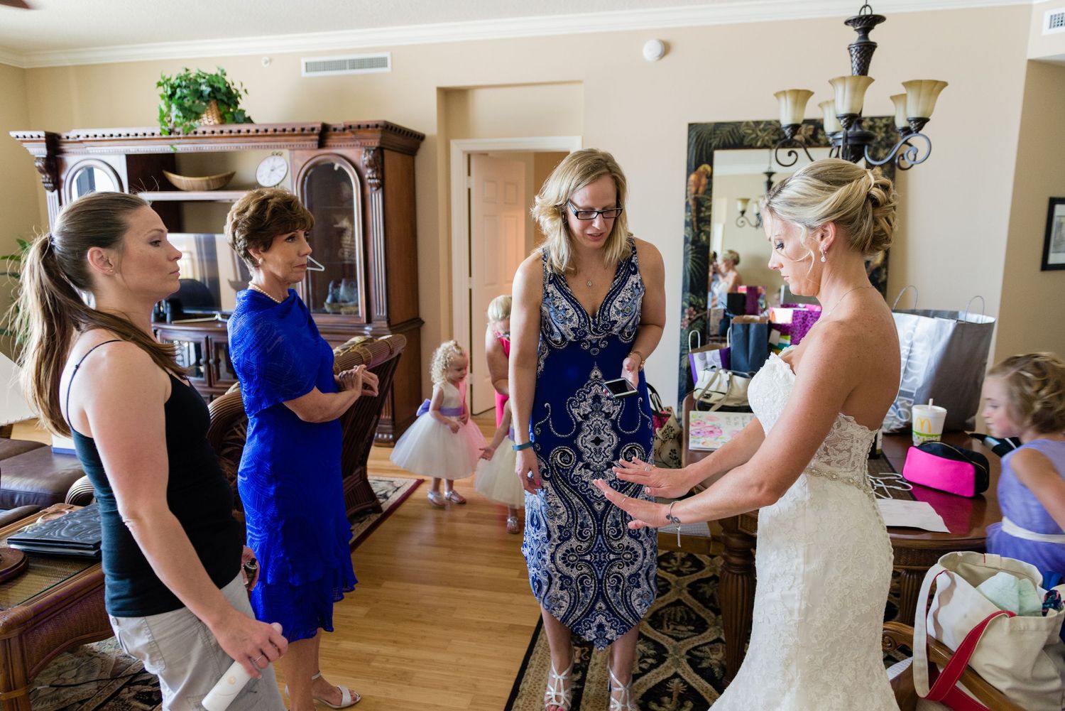Bride in white gown sharing a joyful moment with bridesmaids in blue dresses during wedding preparations indoors.