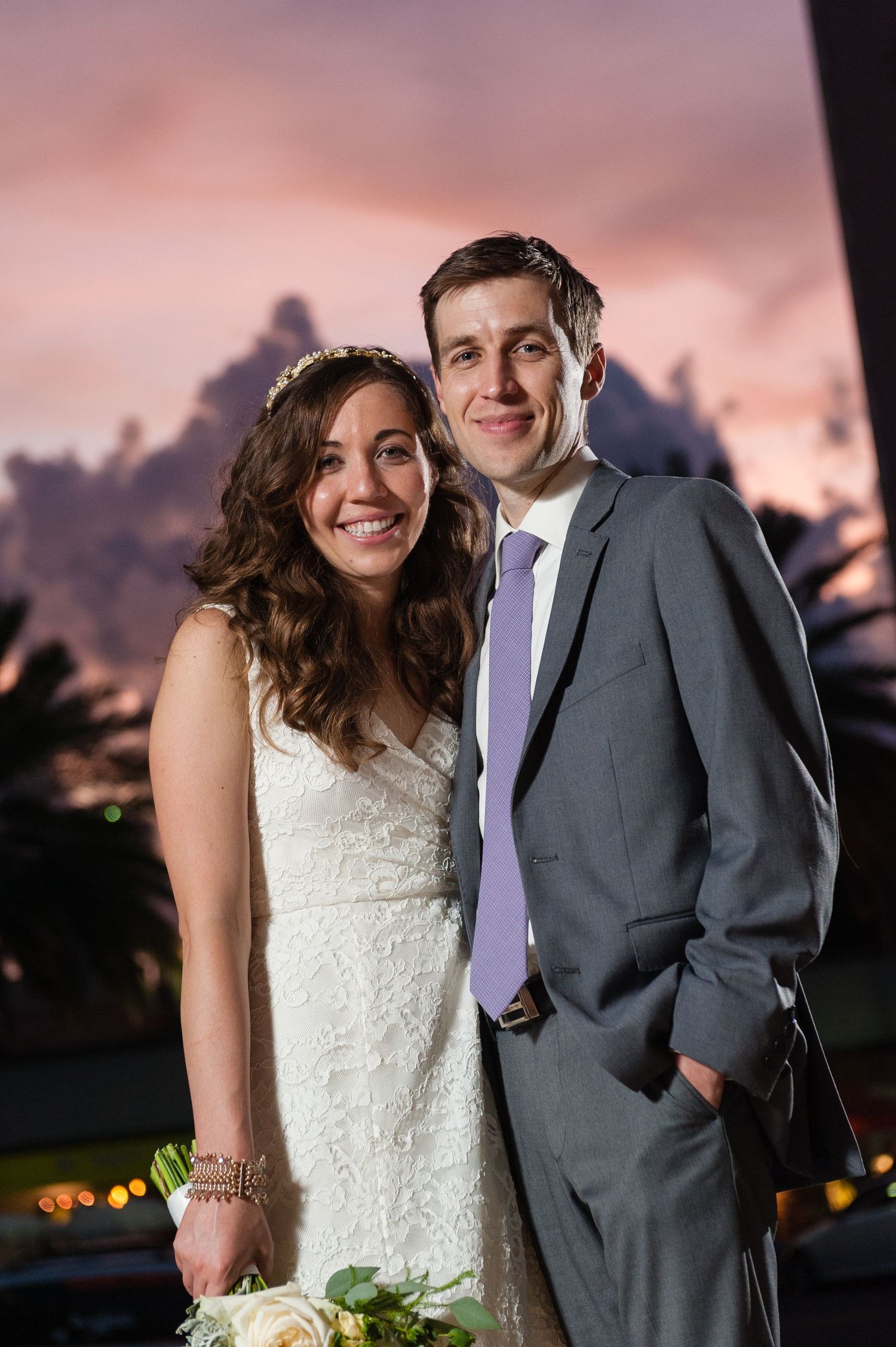 Bride and groom posing together at sunset during their outdoor wedding reception.