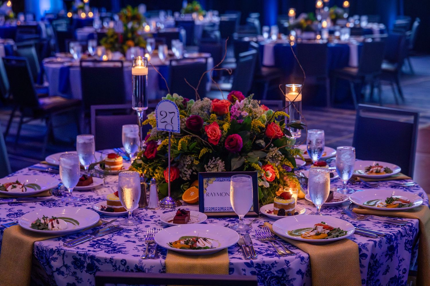 Elegant banquet table set with floral centerpiece, candles, and fine dining place settings.