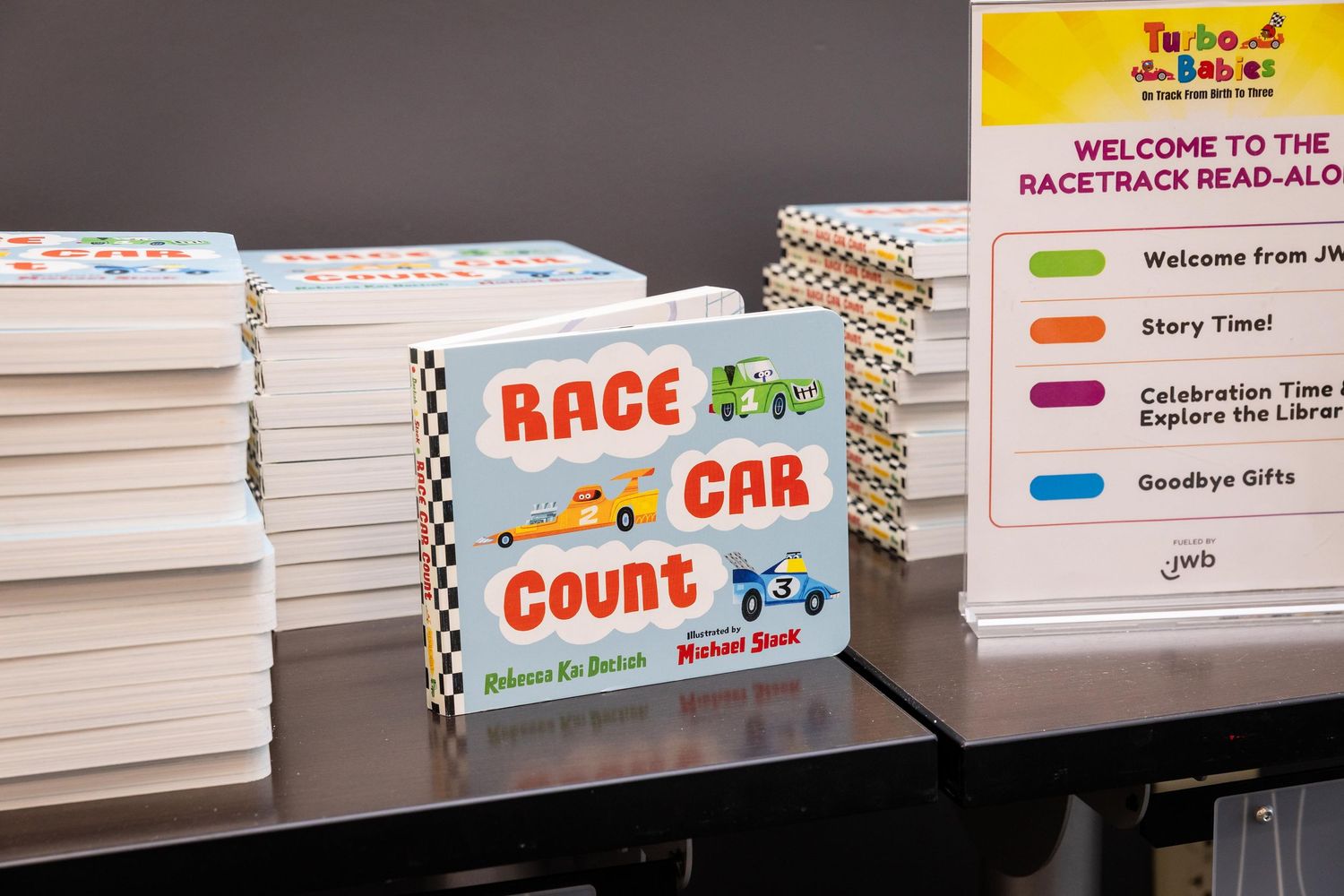 Race Car Count children's book displayed on a table at a Turbo Babies racetrack read-aloud story time event.