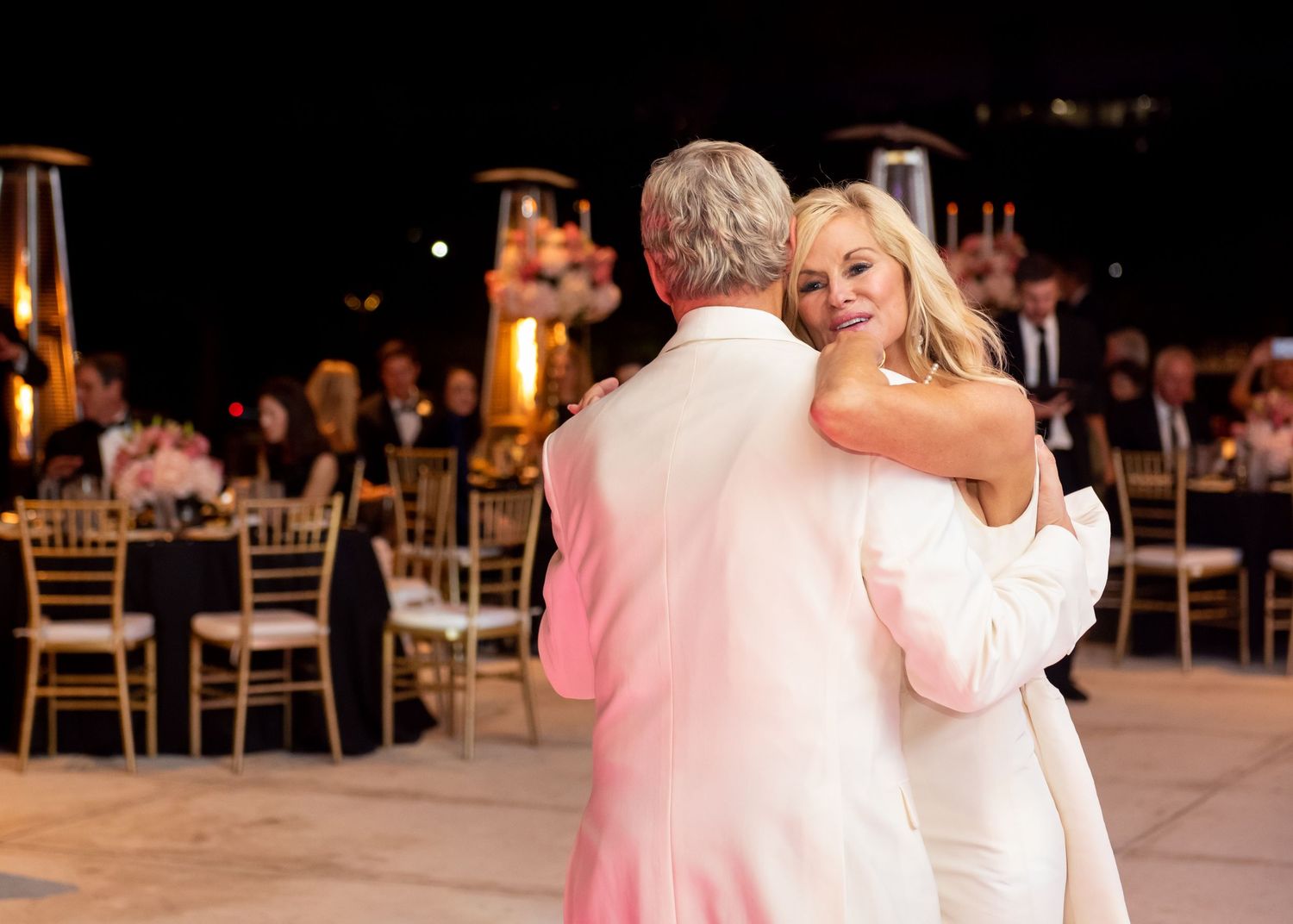 Bride and groom share a romantic first dance at an elegant outdoor wedding reception at night.