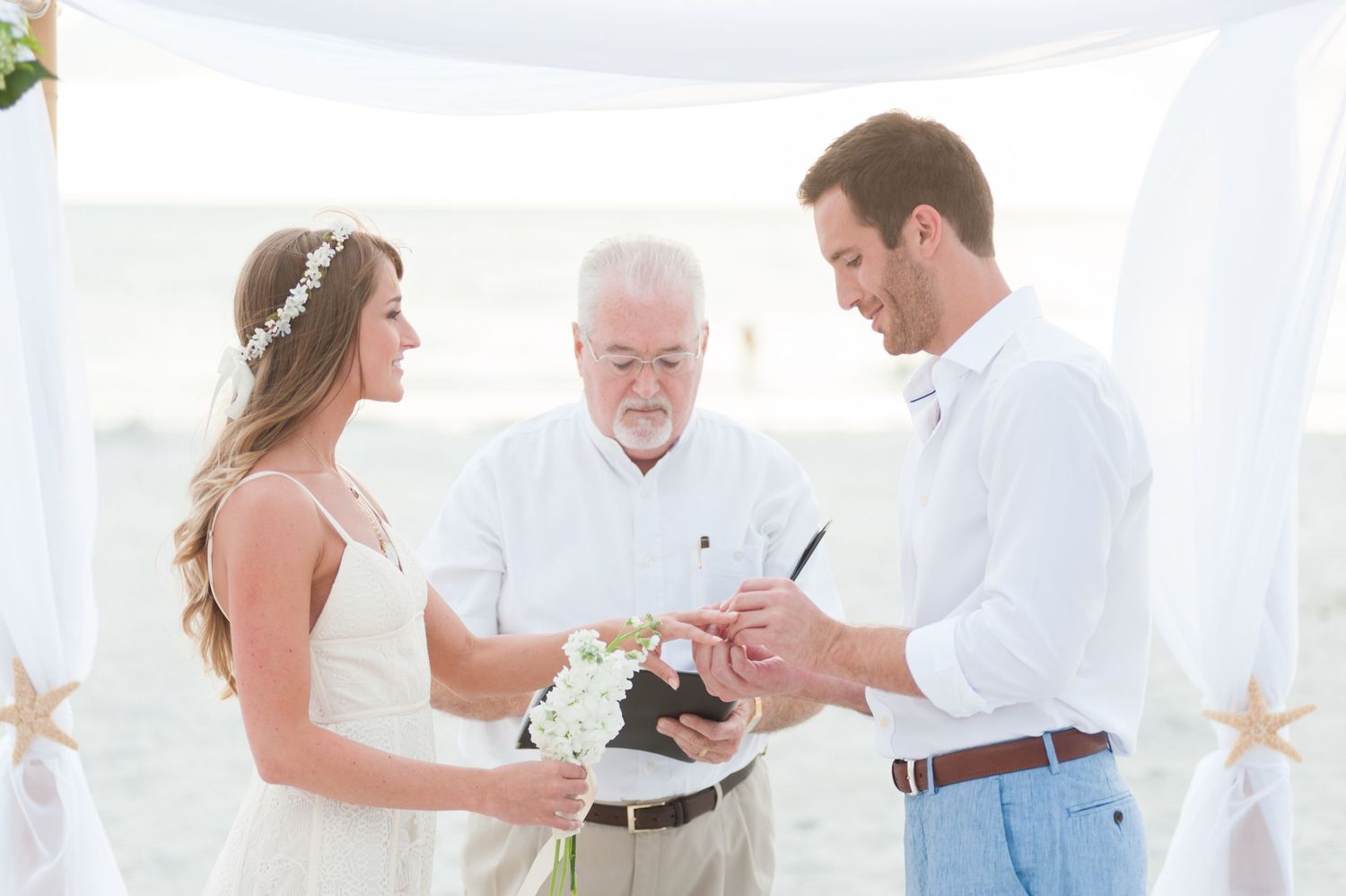 Bride and groom exchange rings during a beach wedding ceremony with an officiant on Treasure Island, Florida.