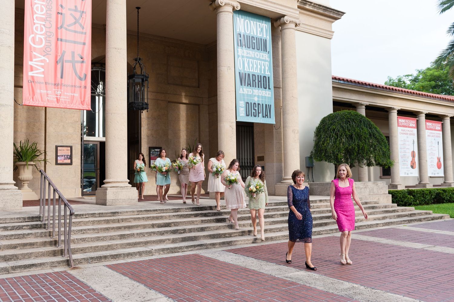 Bridal party in colorful dresses descending steps of Museum of Fine Arts building before wedding.