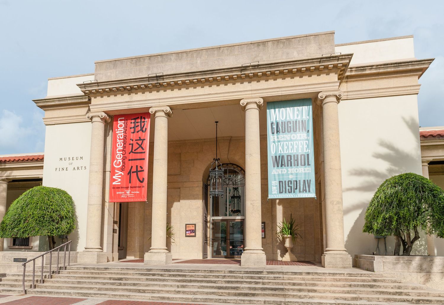 The exterior of a Museum of Fine Arts building with red banners and classical columns.