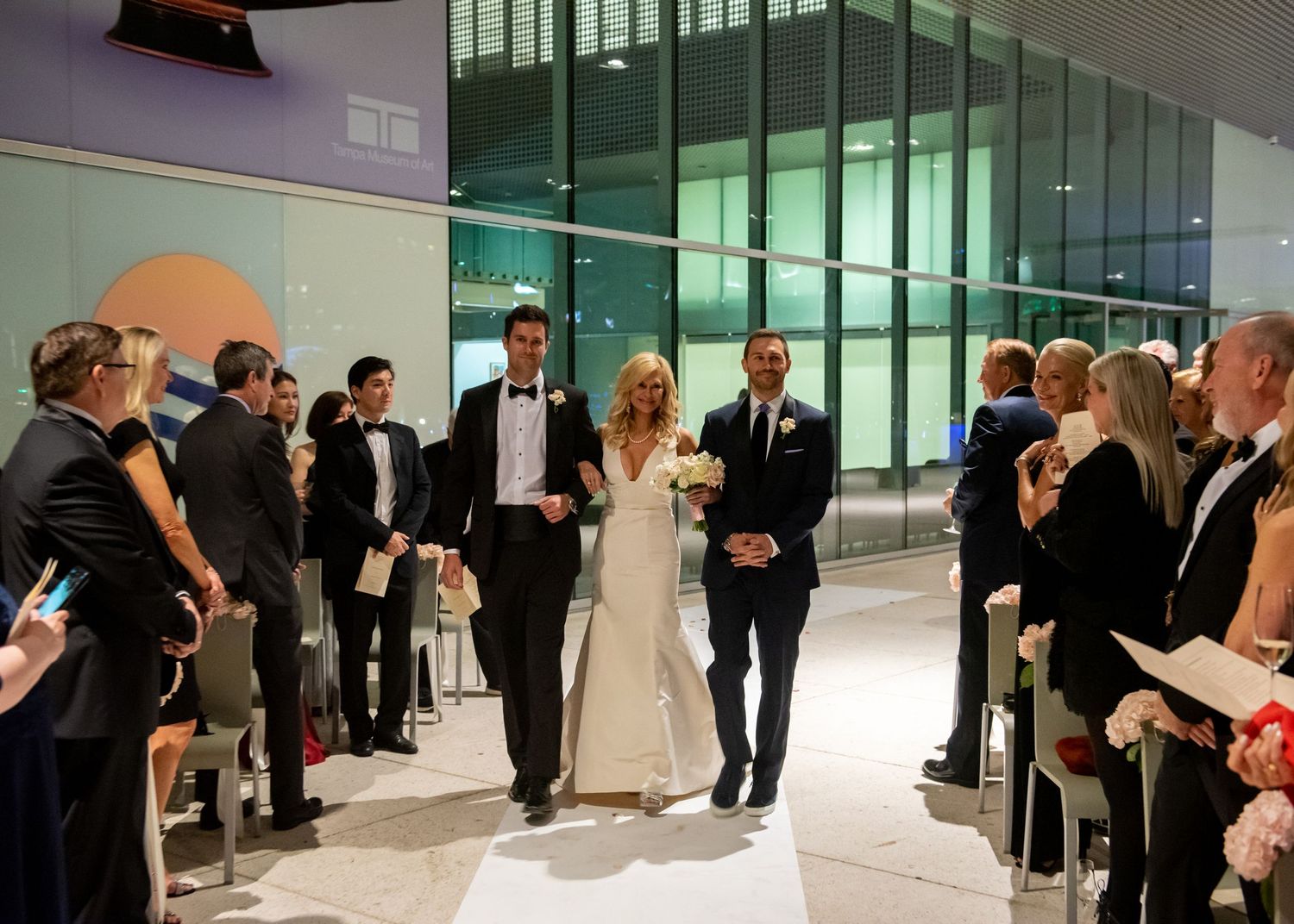 Bride and groom walk down the aisle together during an elegant indoor wedding ceremony.