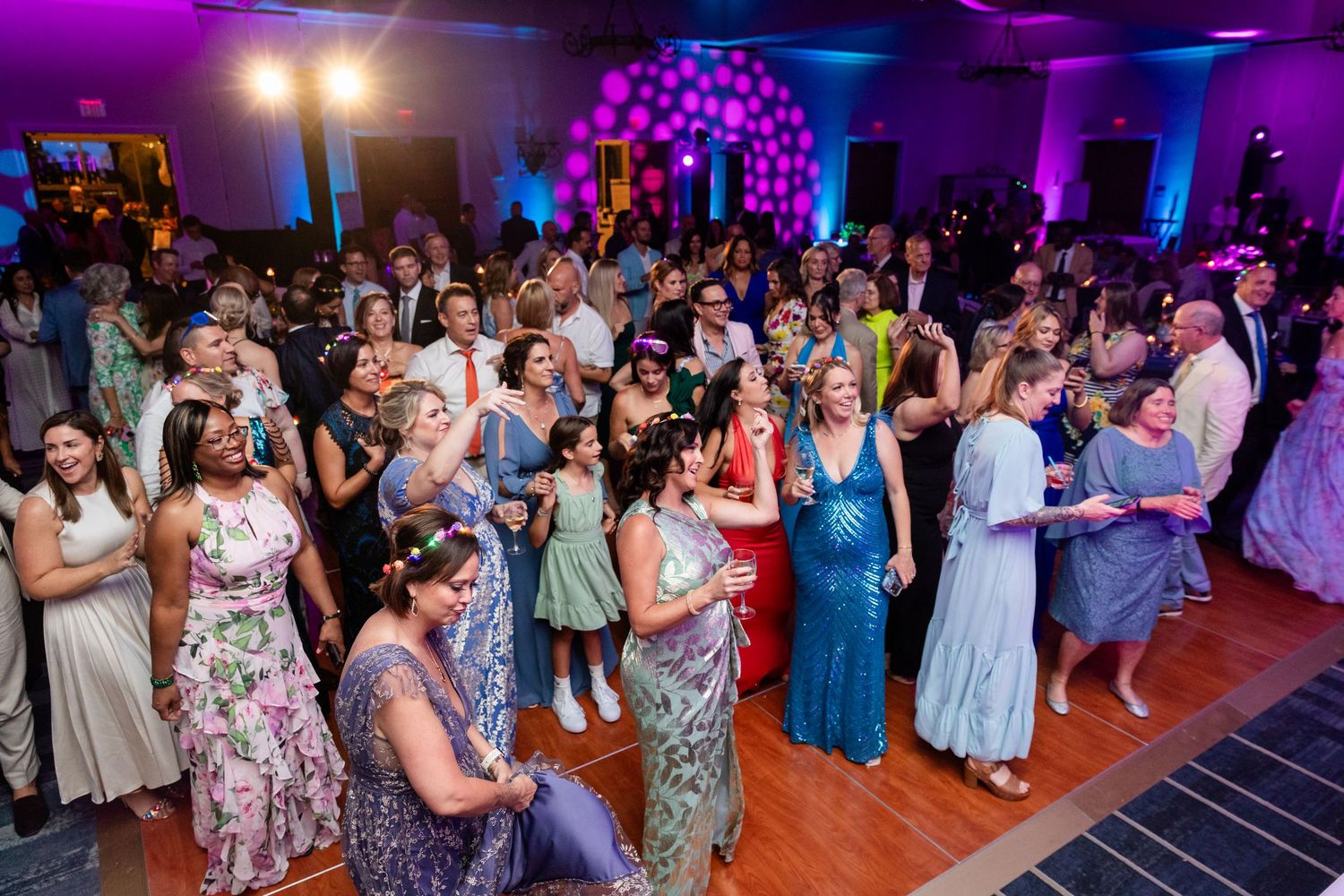 Large crowd of elegantly dressed guests enjoying a wedding reception on a dance floor.