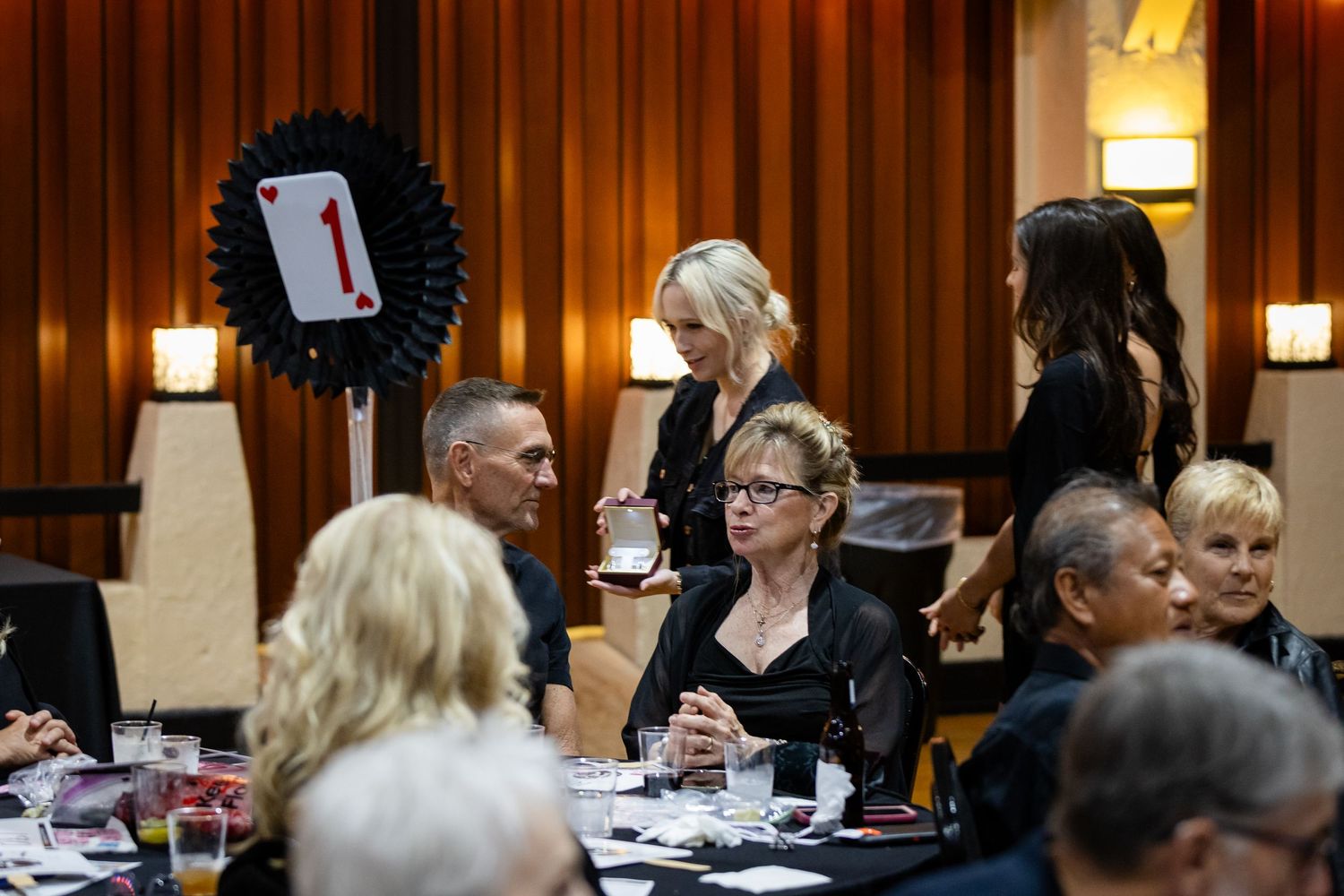 Guests seated at decorated tables during a casino-themed gala with playing card table markers.