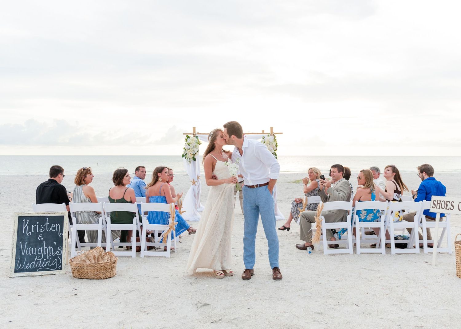 Newlyweds kiss before seated wedding guests on a beautiful sandy beach on Treasure Island, Florida.