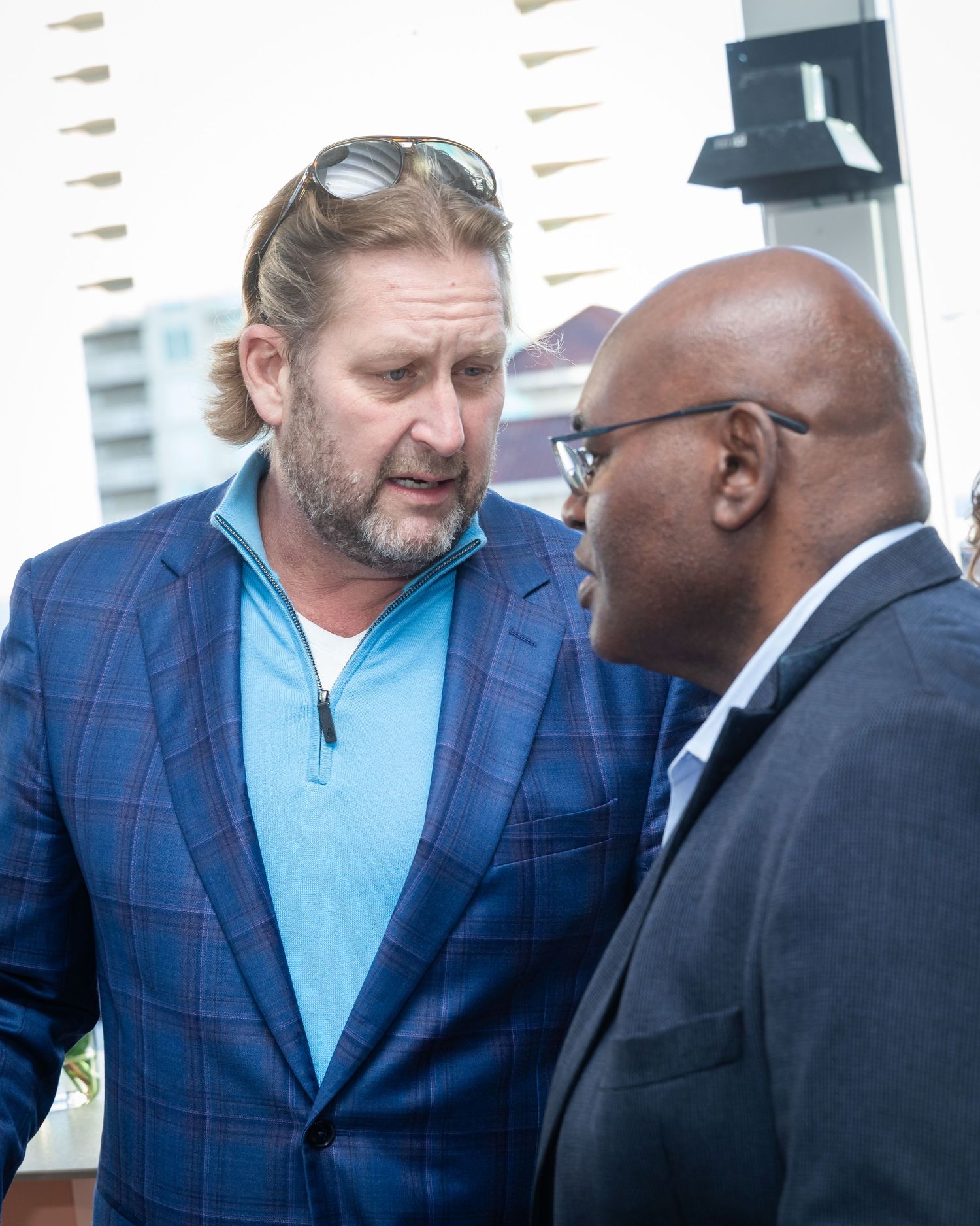 Two men in business casual attire engage in conversation outdoors at a professional networking event.