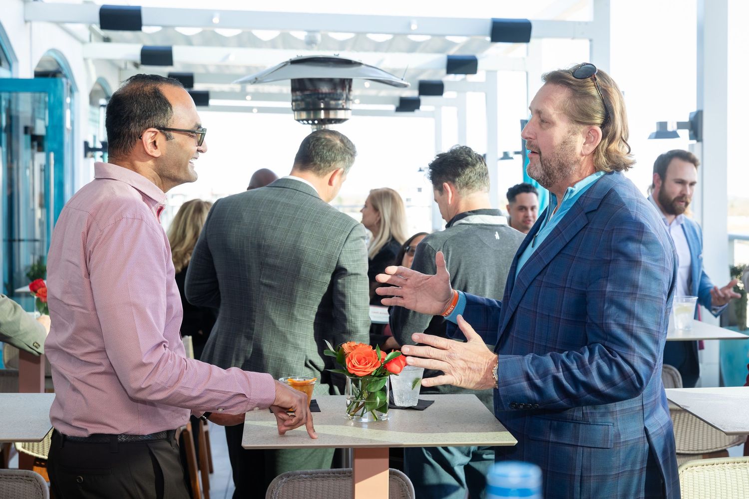 Business professionals networking at an outdoor rooftop event, engaged in conversation at a social gathering.